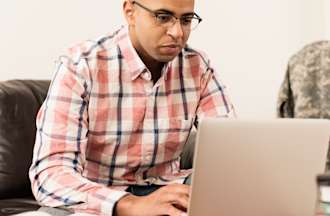 [Featured Image] A man studies for the NCEES PE exam at his laptop in his living room.