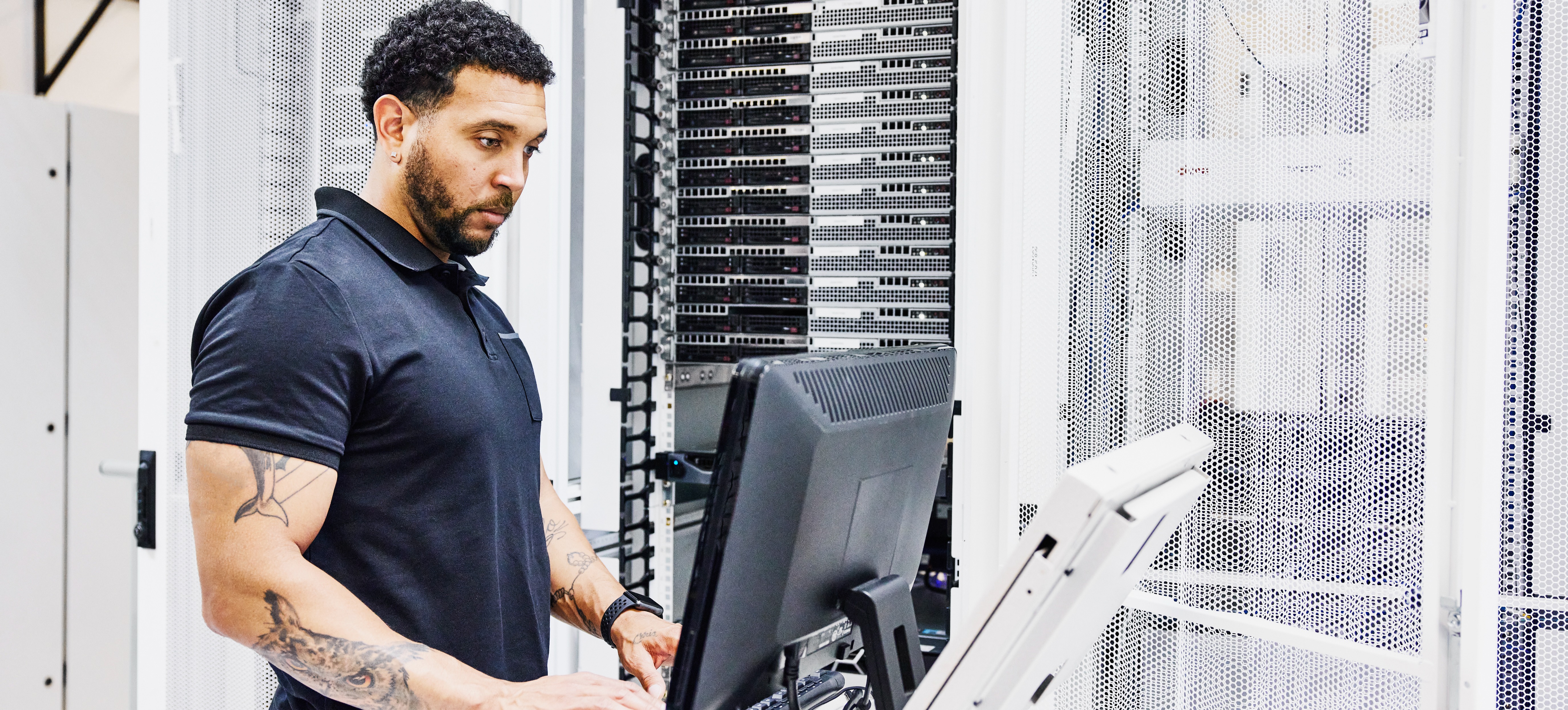 [Featured Image] A male application architect is on a computer, building the structural components of an application in the server room.
