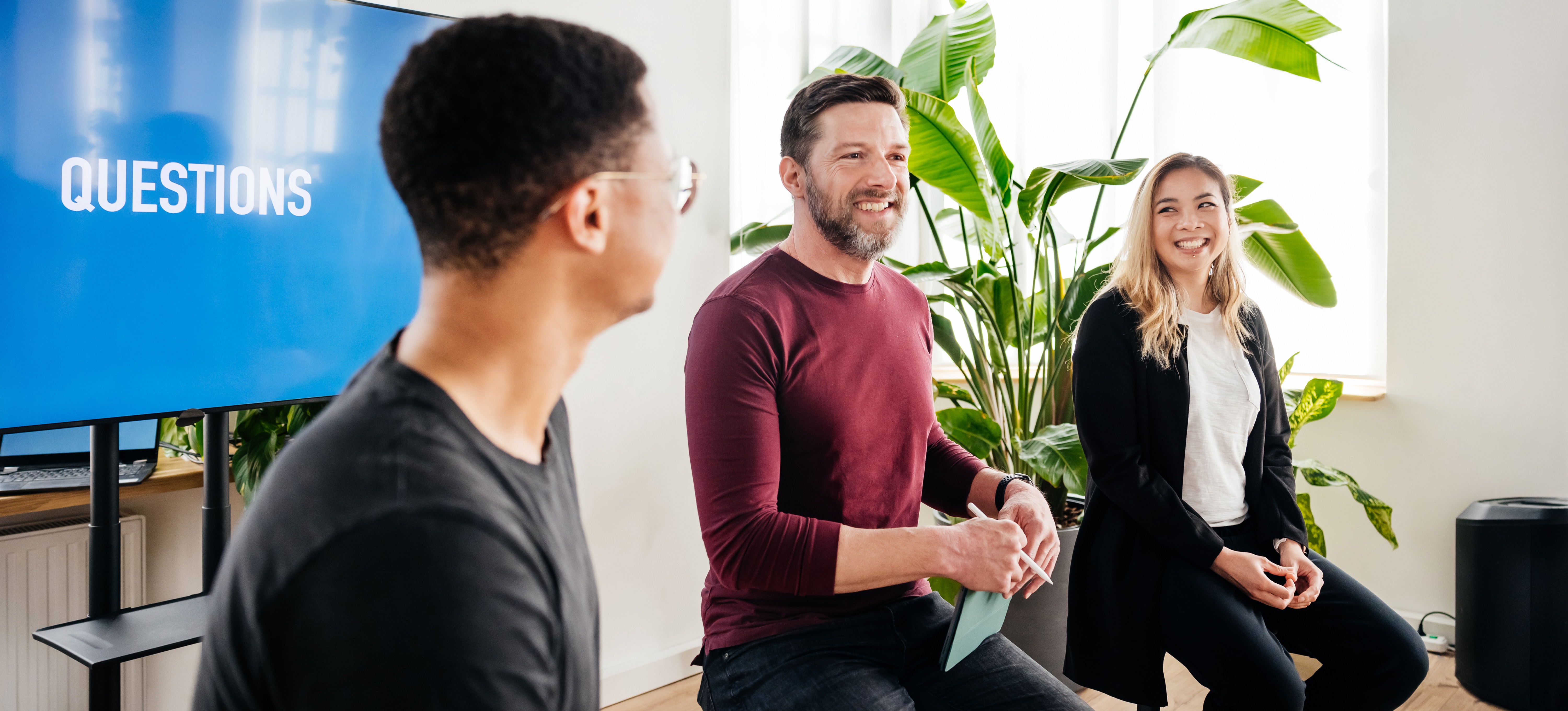 [Featured Image] Three speakers sit in front of a screen that reads “Questions” as they complete a discussion on neuro-symbolic AI.
