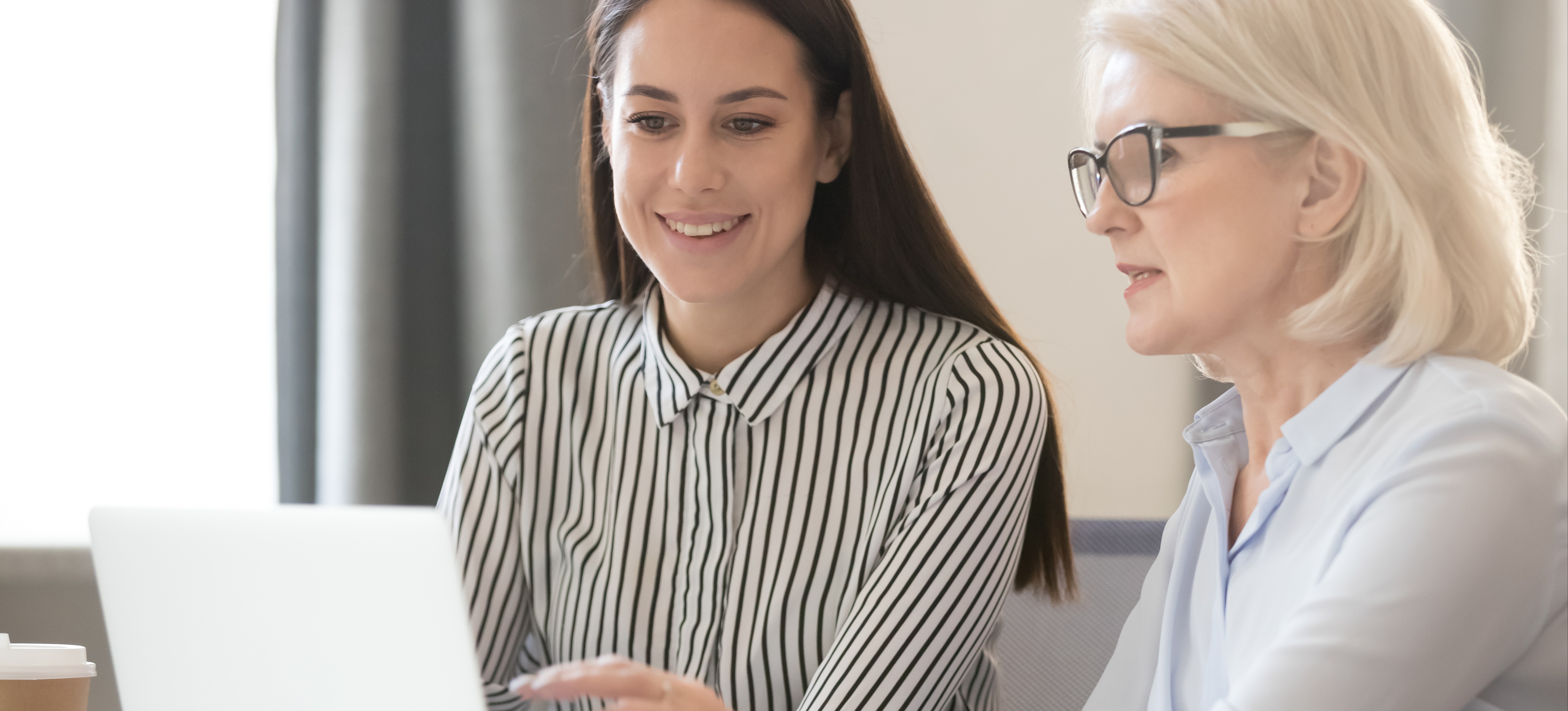 [Featured Image] A career coach talks with her client as they both look at a computer screen.