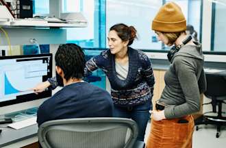 [Featured image] A trio of coworkers engaged in data exploration using visual analysis in an office setting. 
