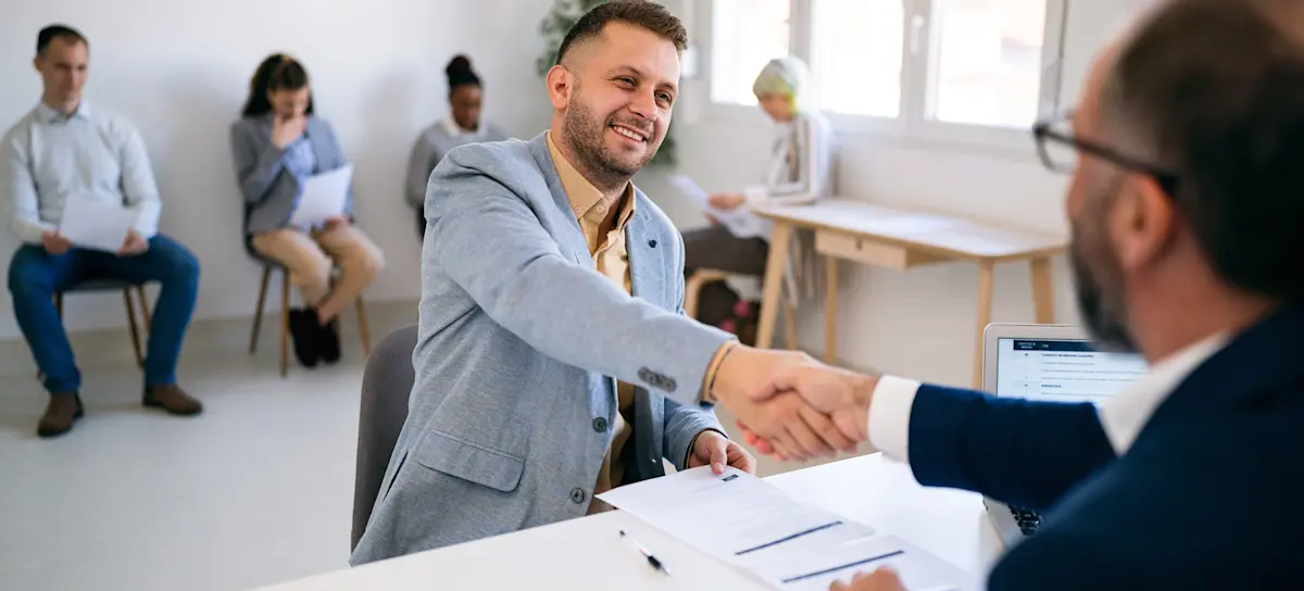 [Featured Image] A recruiter and a candidate shaking hands in a professional workplace setting, smiling while discussing common R programming interview questions.
