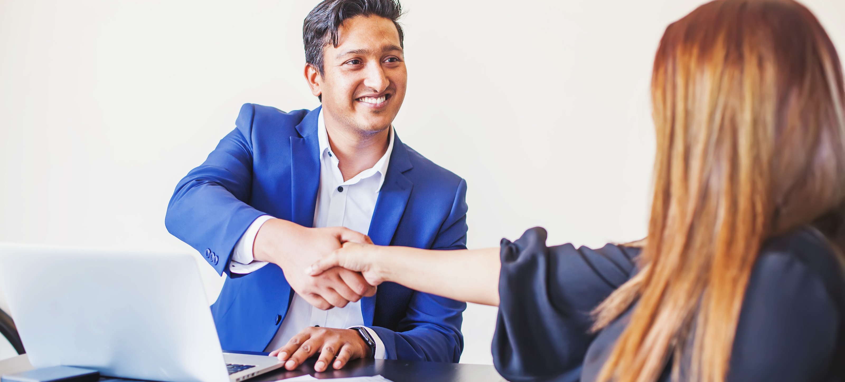[Featured Image] Two people shake hands after a job interview for a data science job for freshers. 
