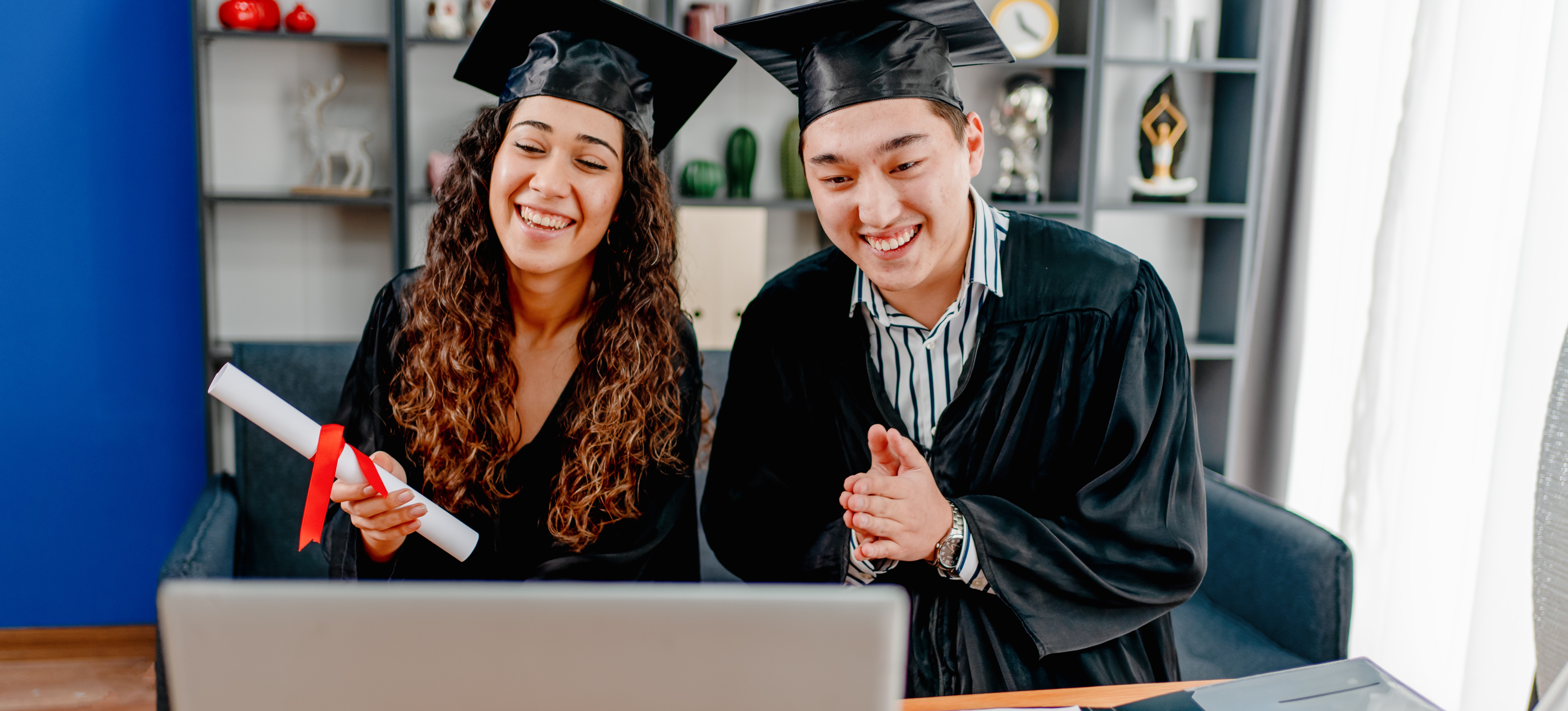 [Featured image] Two PhD students in caps and gowns celebrate their new degrees on a video call.