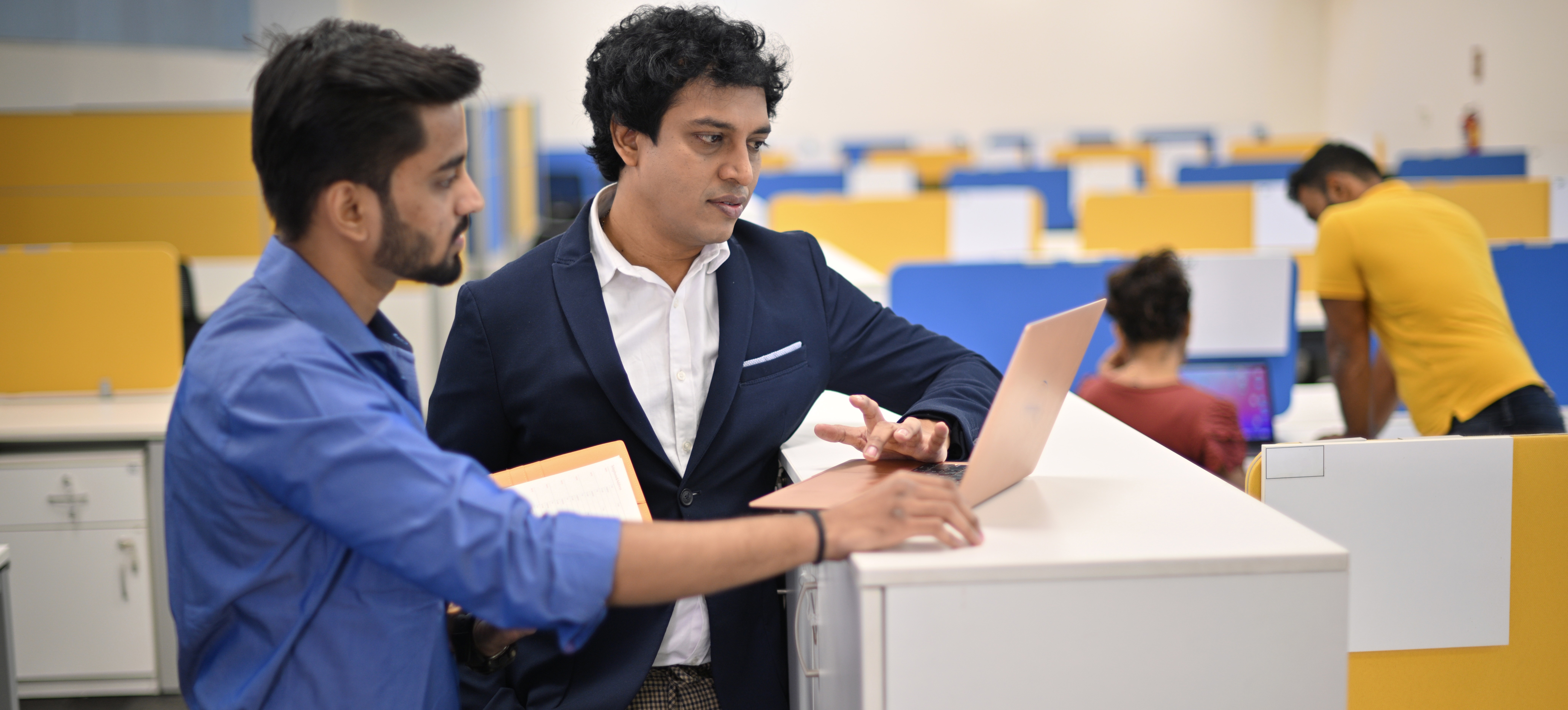 [Featured Image]: A supervisor in a high-paying IT job looks at a laptop with a co-worker as they discuss a current project.