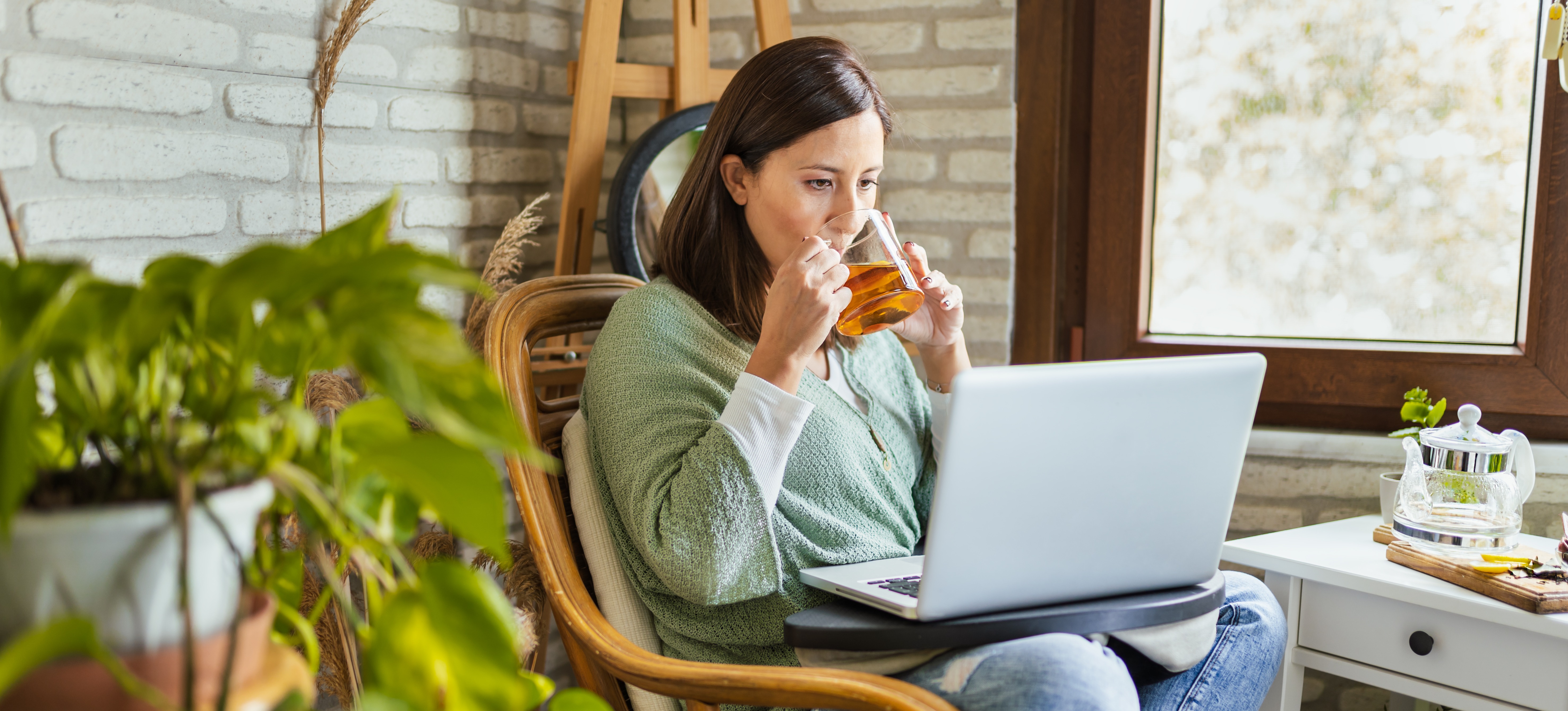 [Featured Image] A woman drinks tea and works on a laptop, learning how to use ChatGPT.