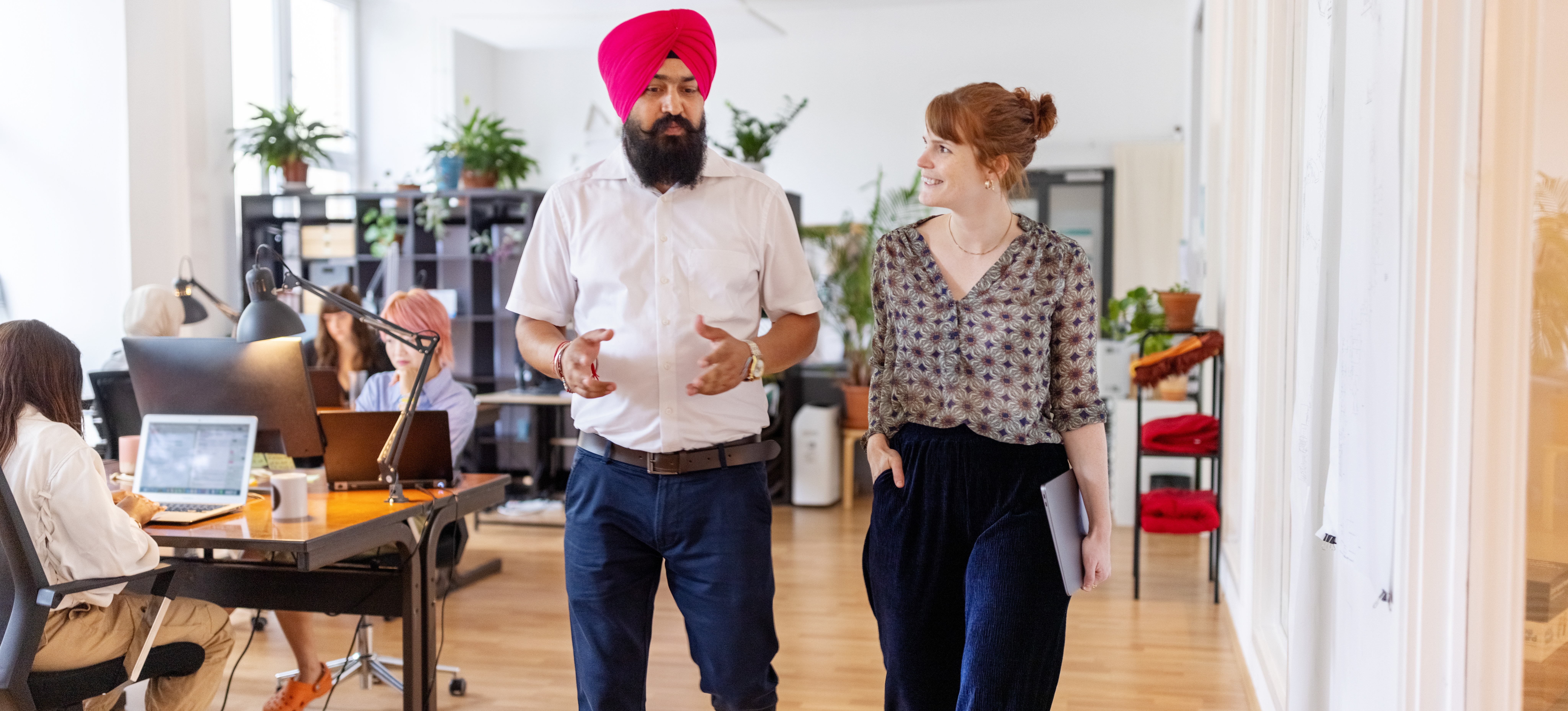 [Featured Image] Coworkers walk whilst discussing how to set boundaries at work.
