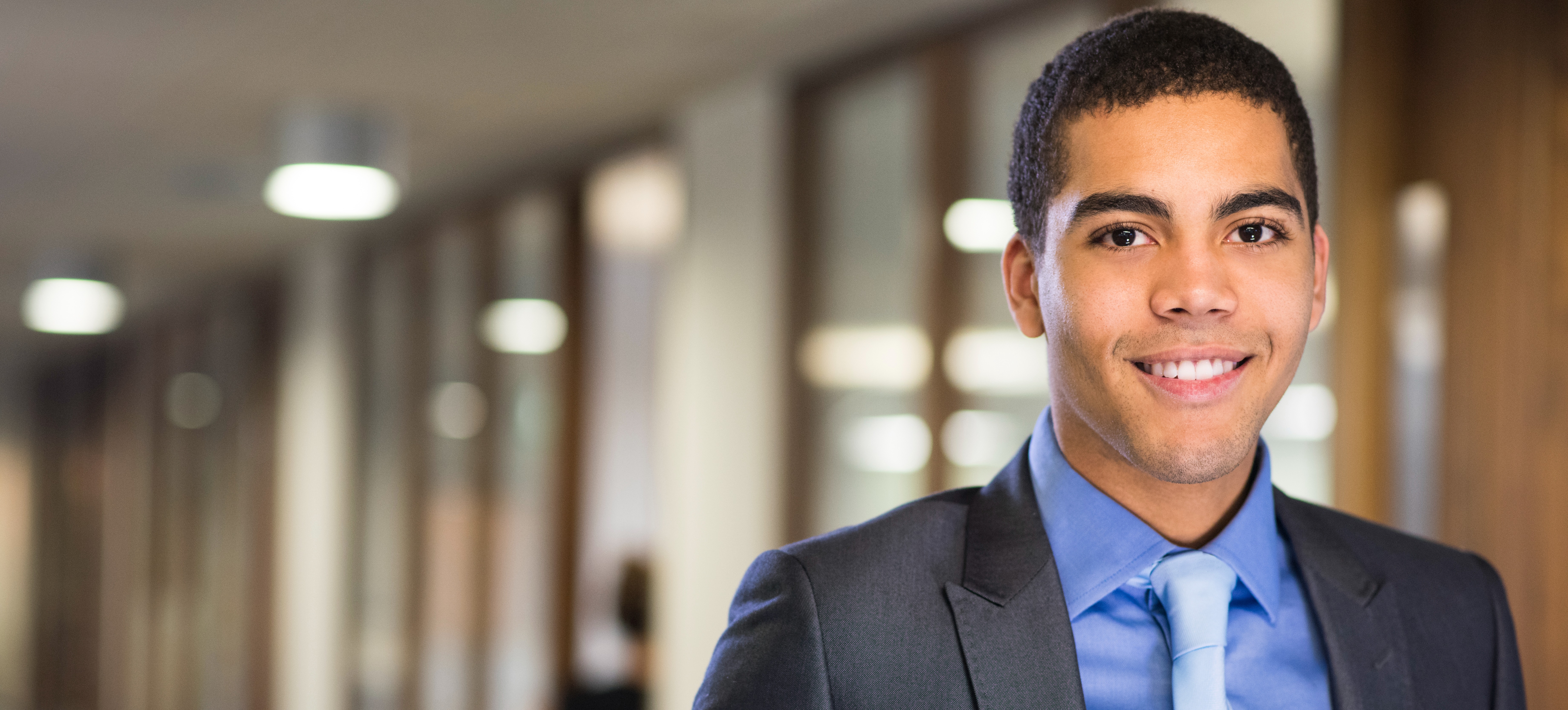 [Feature image] A recent graduate standing proudly in his first placement.