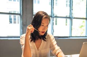 [Featured Image] A front-end developer in a white blouse sits at a large table near windows and preps responses to interview questions.