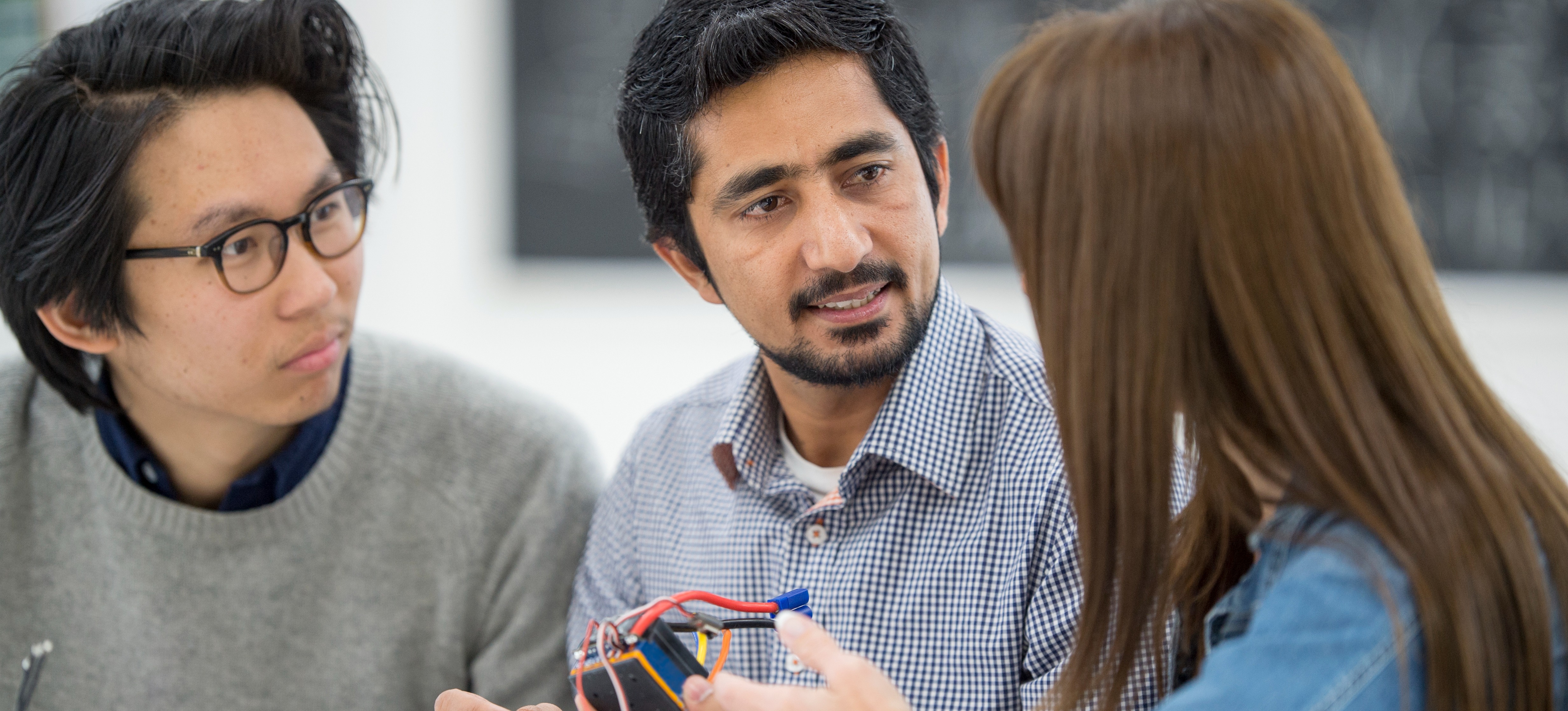 [Featured Image] Two electrical engineers mentoring a learner discuss electrical engineer resumes and CVs and what to include to get noticed. 
