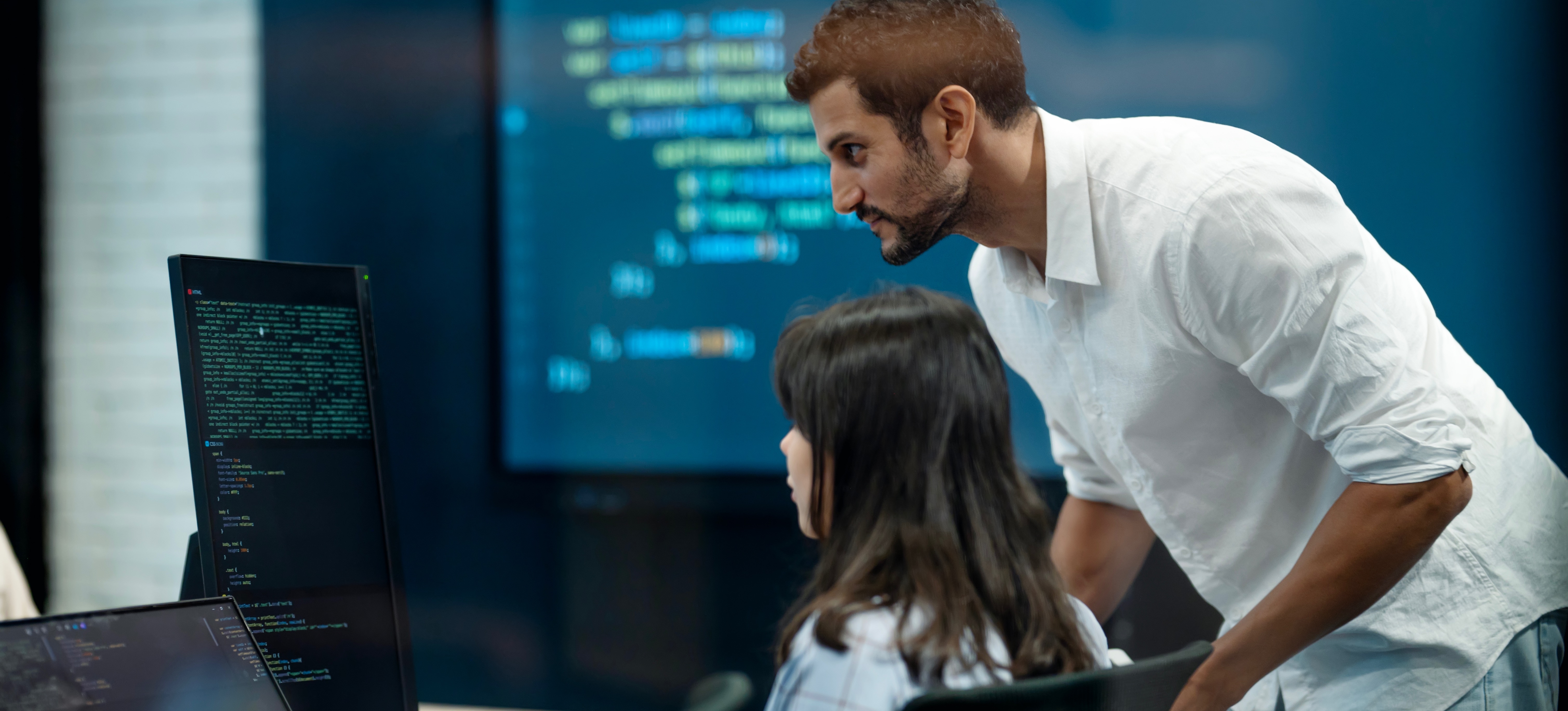 [Featured Image]: AI data trainers working together in an office environment, analyzing AI-related codes on their computers.