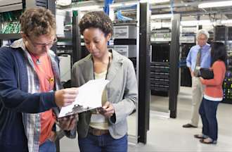 [Featured Image] A group of employees look over some information while performing their cyber security jobs in Atlanta.