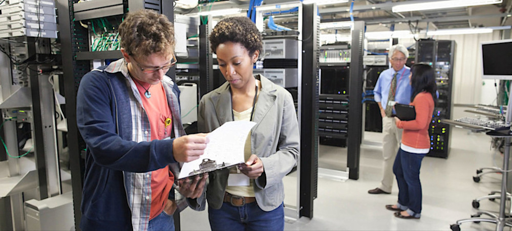 [Featured image] A group of employees looks over information while performing their cyber security jobs in Atlanta.