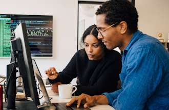 [Featured Image] Two data scientists work together on a desktop computer.