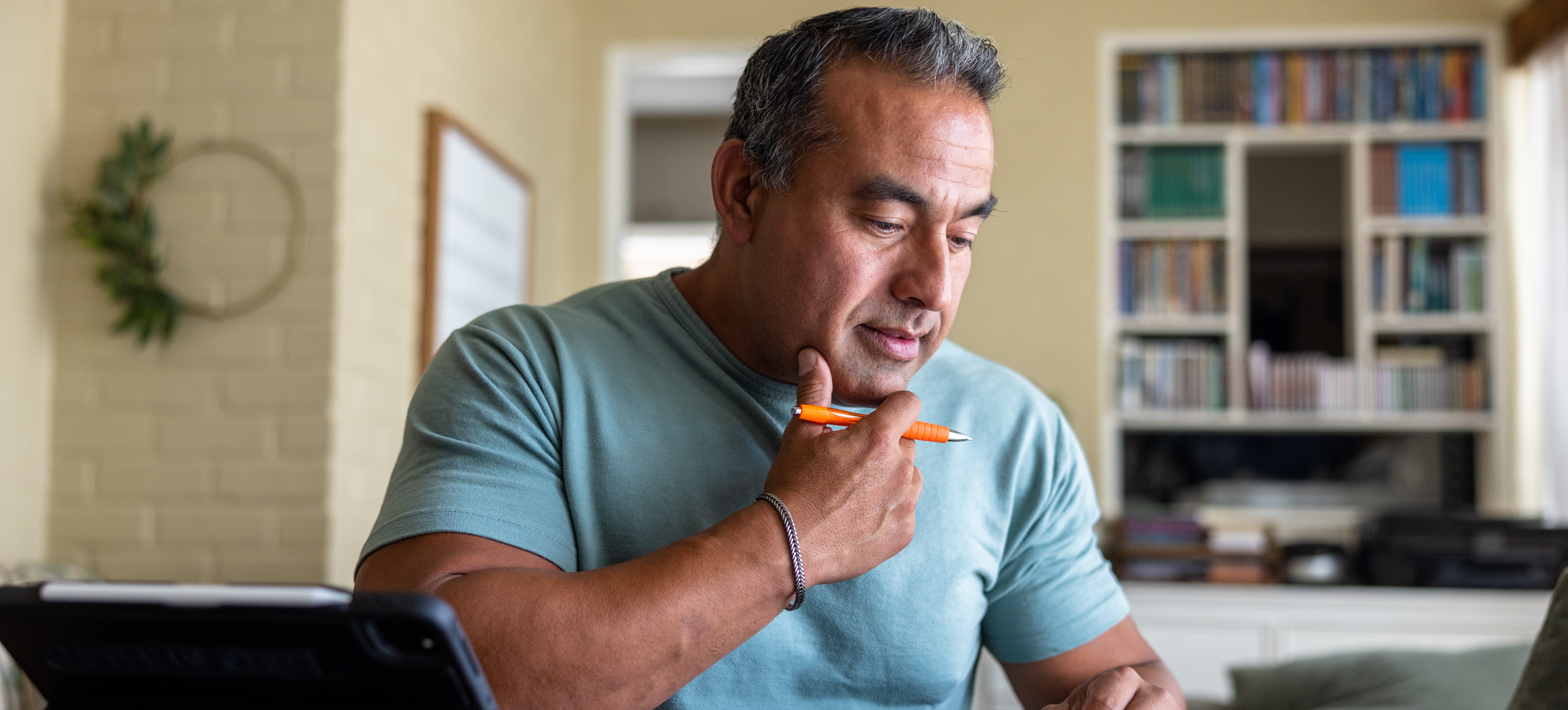 [Featured Image] A learner sits at a table at home and uses a tablet, calculator, and notebook as they work on earning a part-time MBA.
