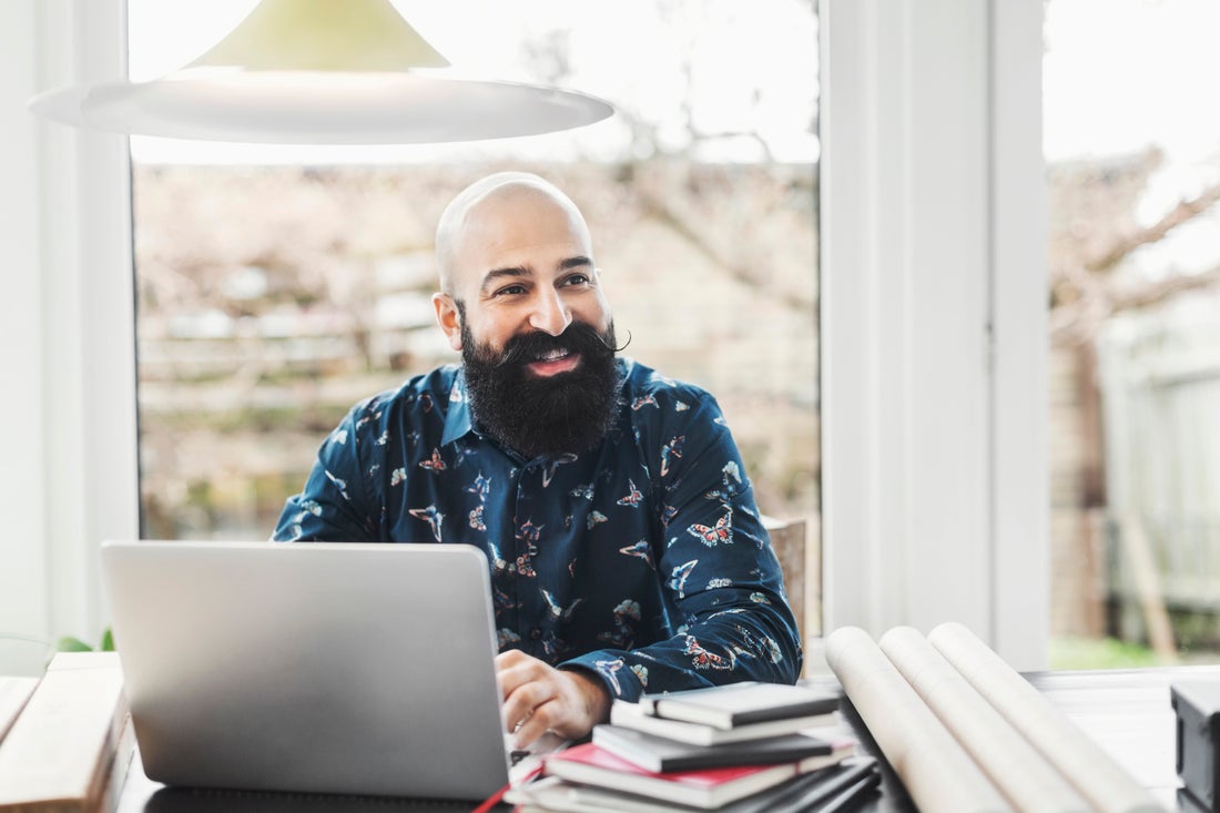 [Featured image] Man sits at his desk in front of his laptop and smiles as he discovers that his Google ads conversion setup was successful.