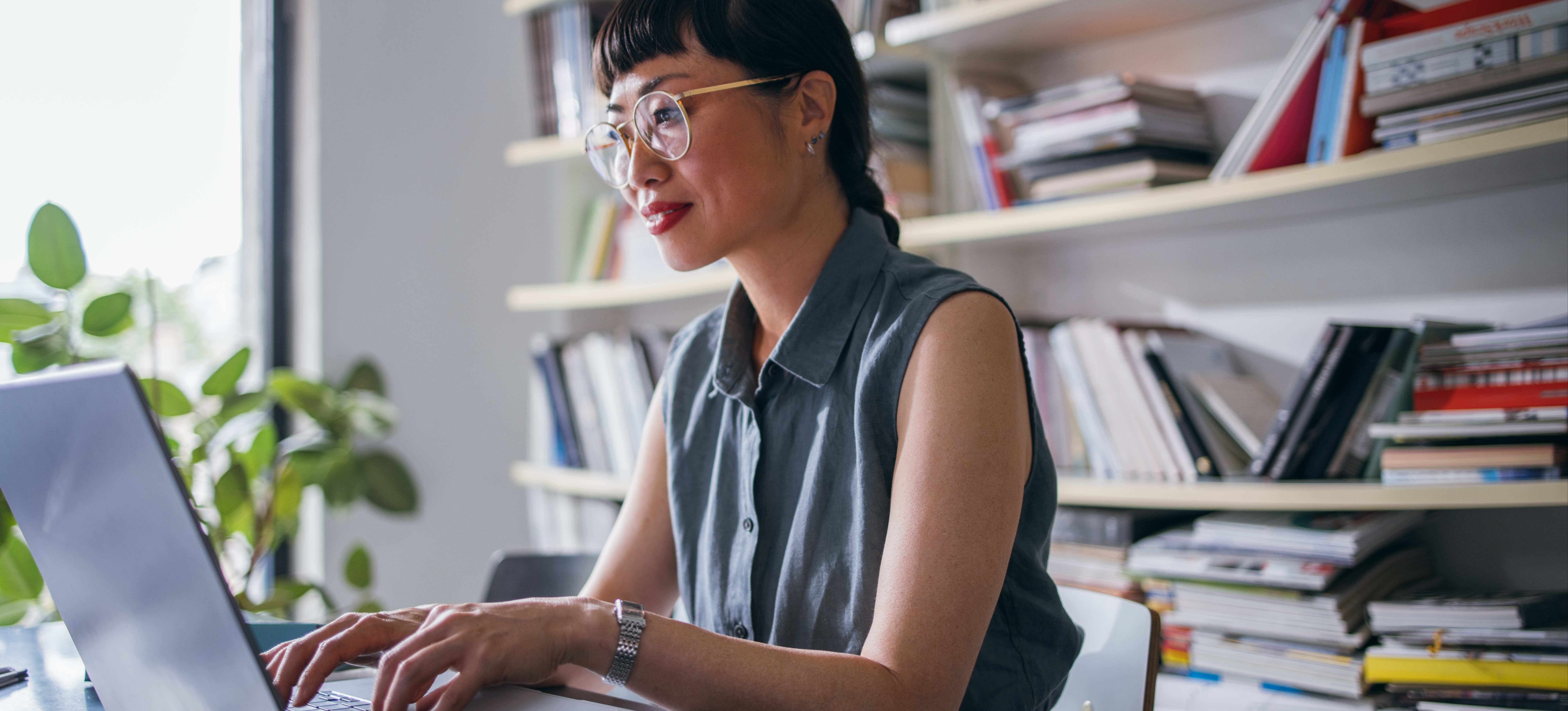 [Hauptbild] Ein Geschäftsmann, der sich für die Lernkultur an seinem Arbeitsplatz engagiert, absolviert einen Kurs auf seinem Laptop, während er in seinem Büro vor einem Regal voller Bücher sitzt.