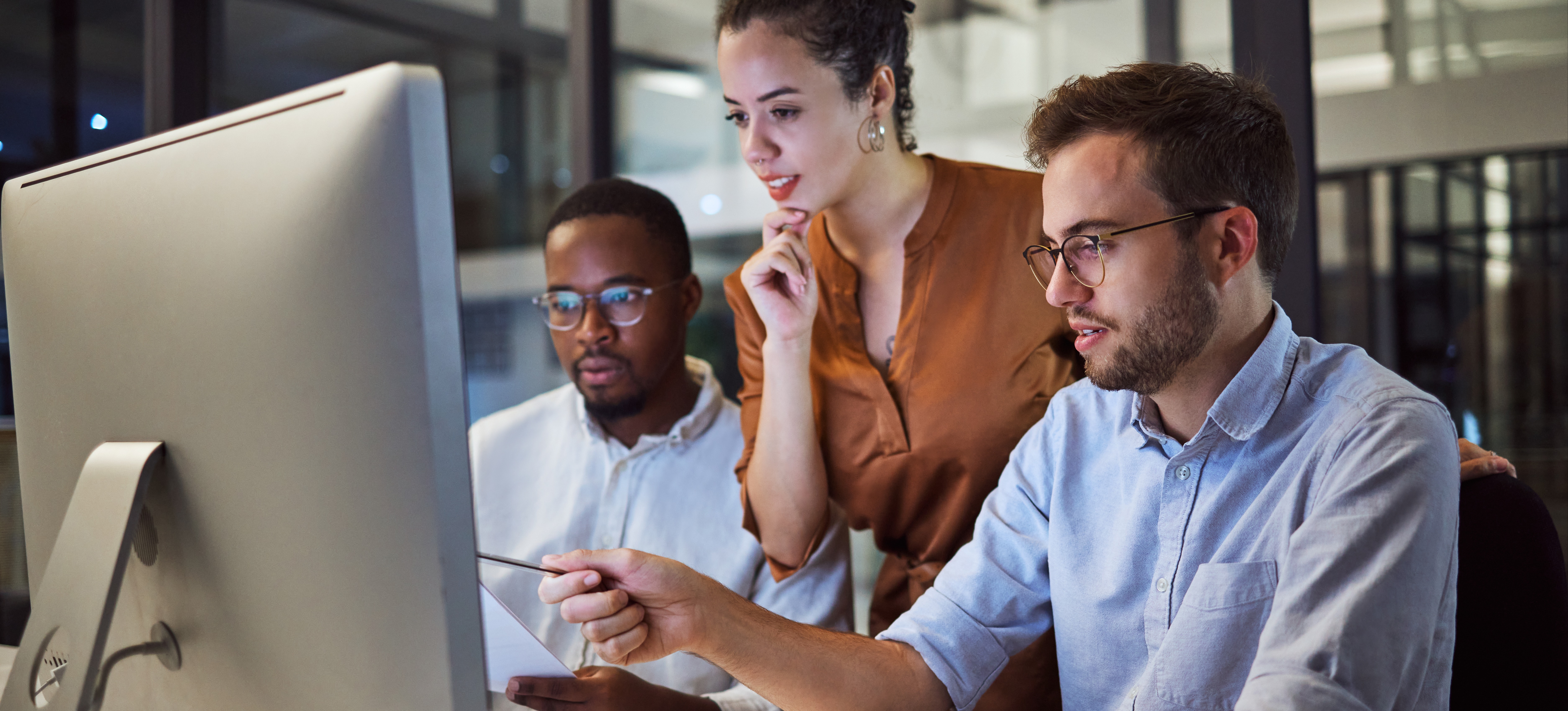 [Featured Image] Three IT professionals discuss IPv4 vs. IPv6 while looking at a computer screen.
