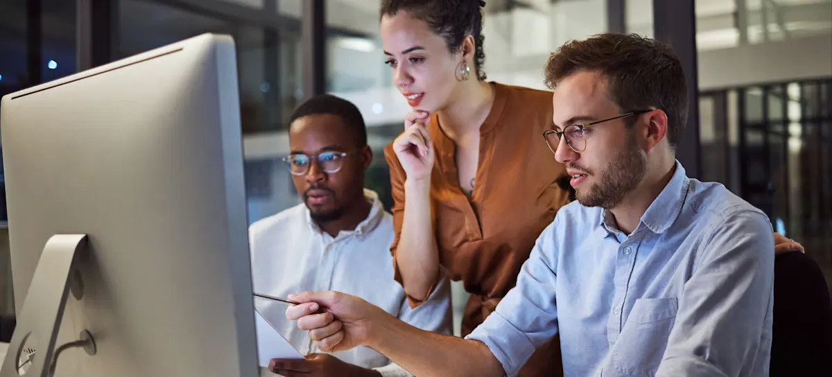 [Featured Image] Three IT professionals discuss IPv4 vs. IPv6 while looking at a computer screen.
