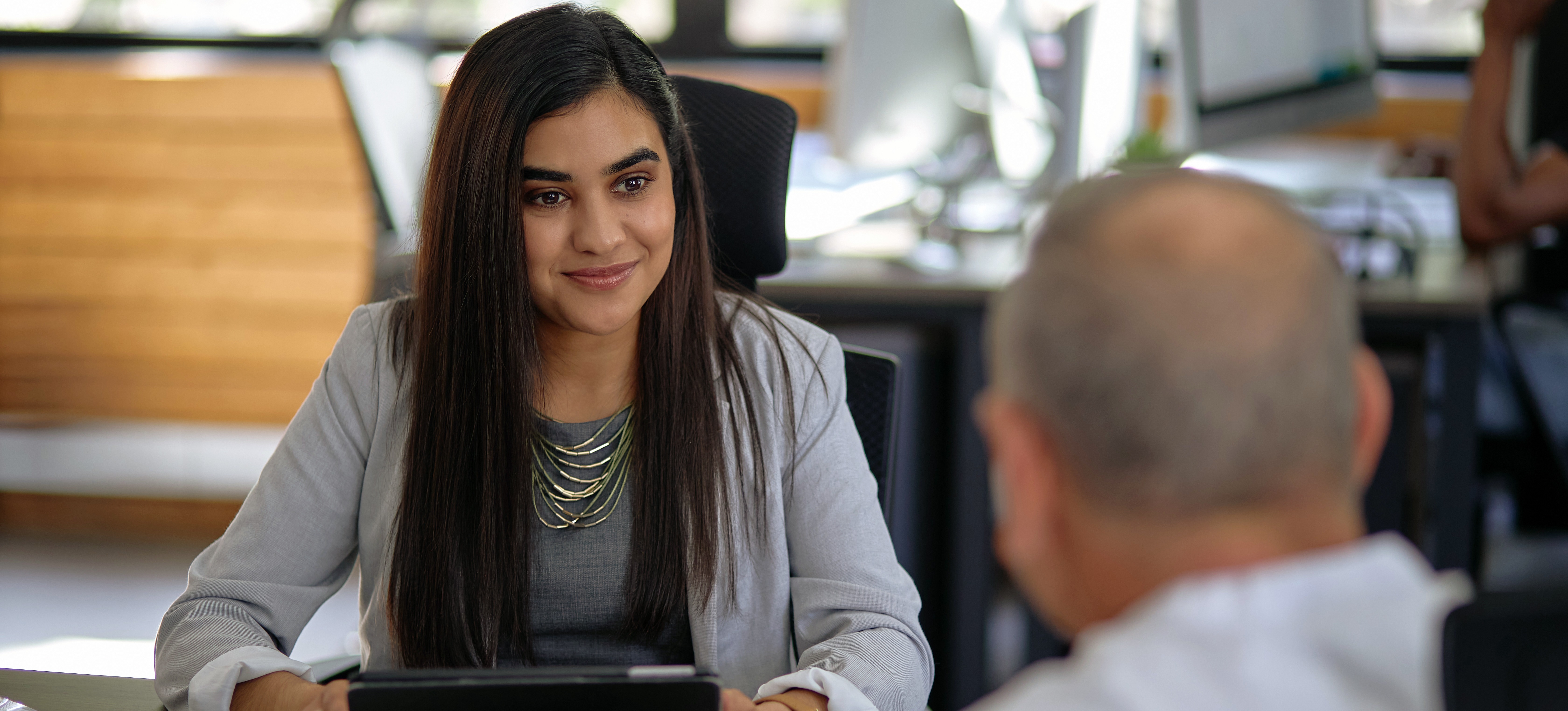 [Featured image] A person in a grey jacket conducts a situational interview with a prospective employee. 