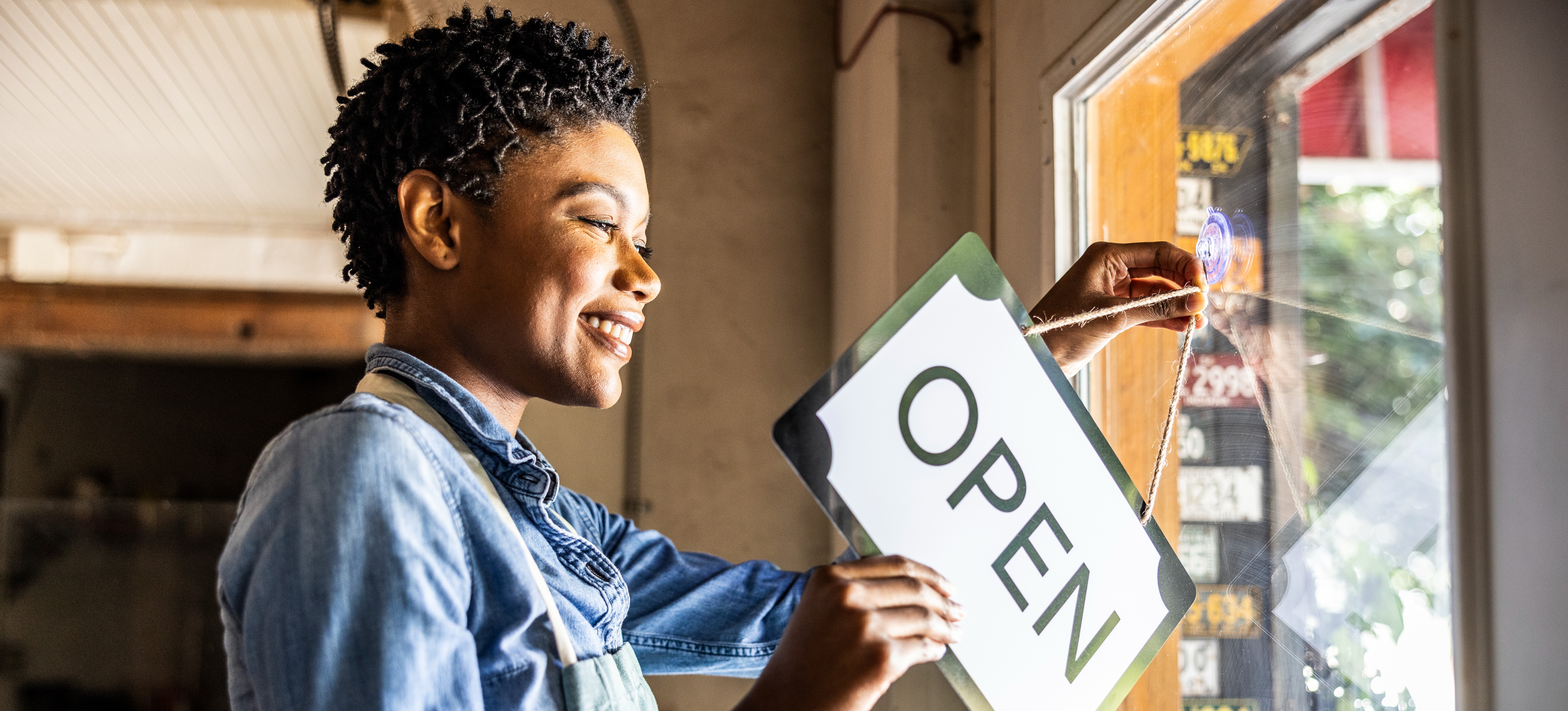 [Feature Image] After sifting through small business ideas and researching how to start a small business, an entrepreneur opens the doors at their brick-and-mortar location.
