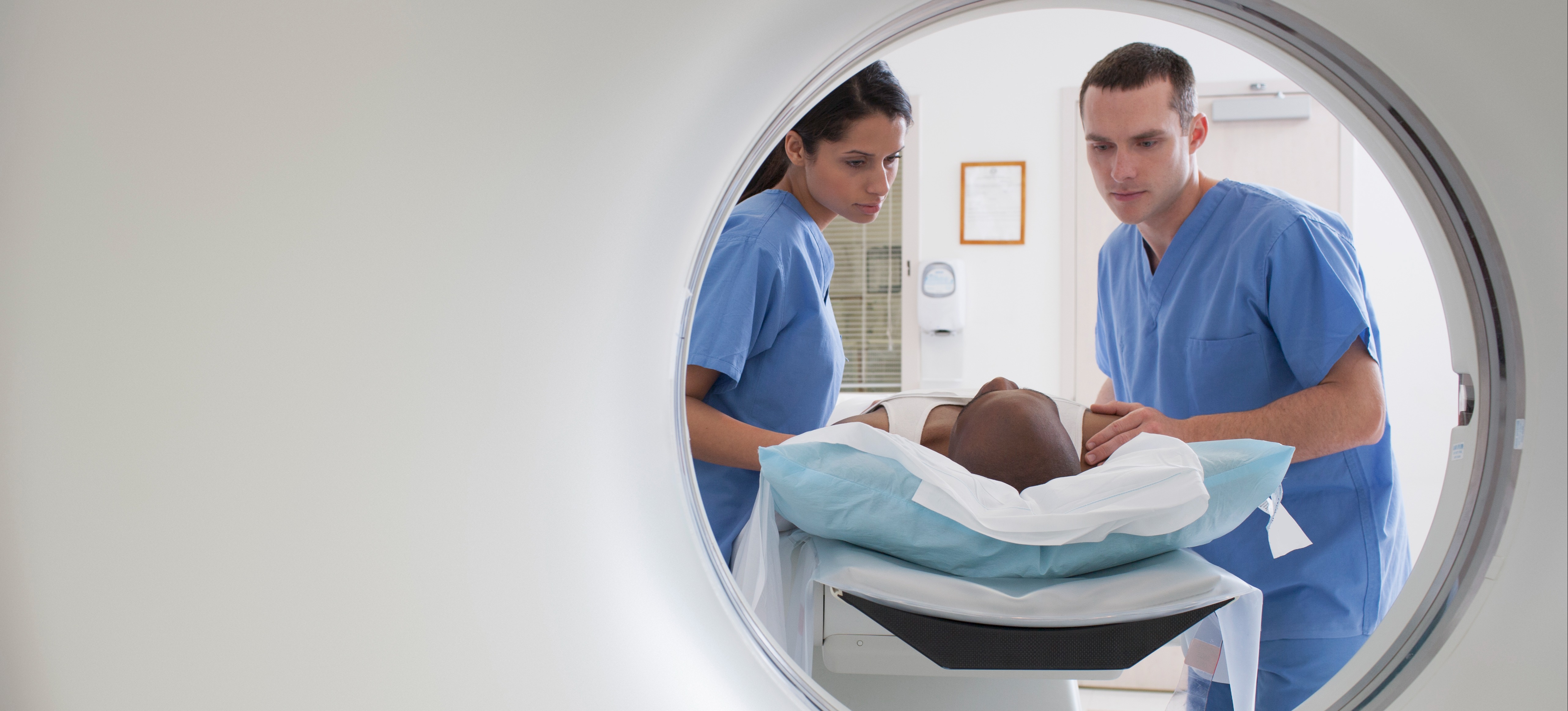 [Featured Image] Two nurses, one male and one female, after taking a machine learning in helathcare course get a patient ready for a CAT scan.