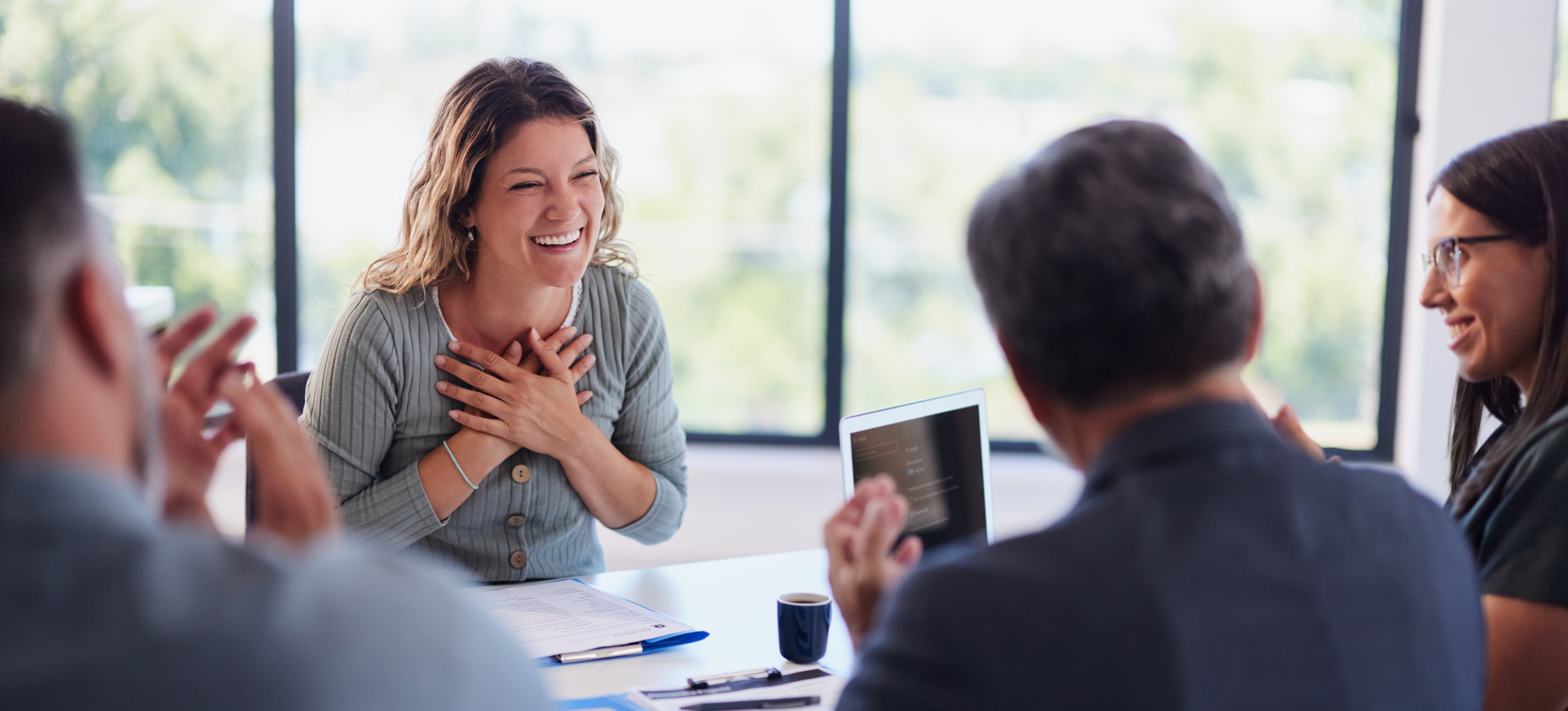 [Featured Image] A group of recruiters interviewing a candidate in a professional setting, reviewing a resume on the table during the discussion about the product manager role.
