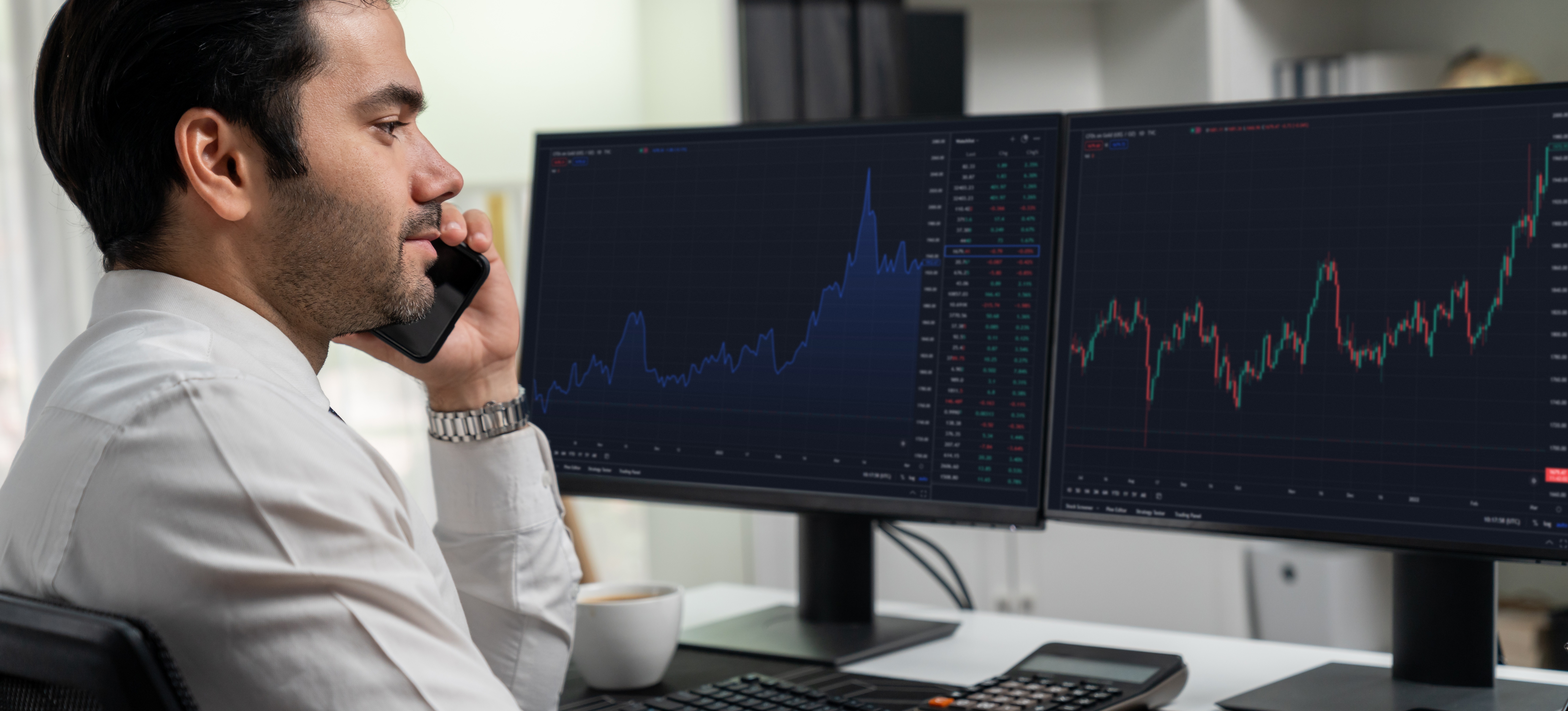 [Featured Image] An investor engages in cryptocurrency arbitrage as they watch market values rise and fall on two computer monitors, while talking on a cell phone.
