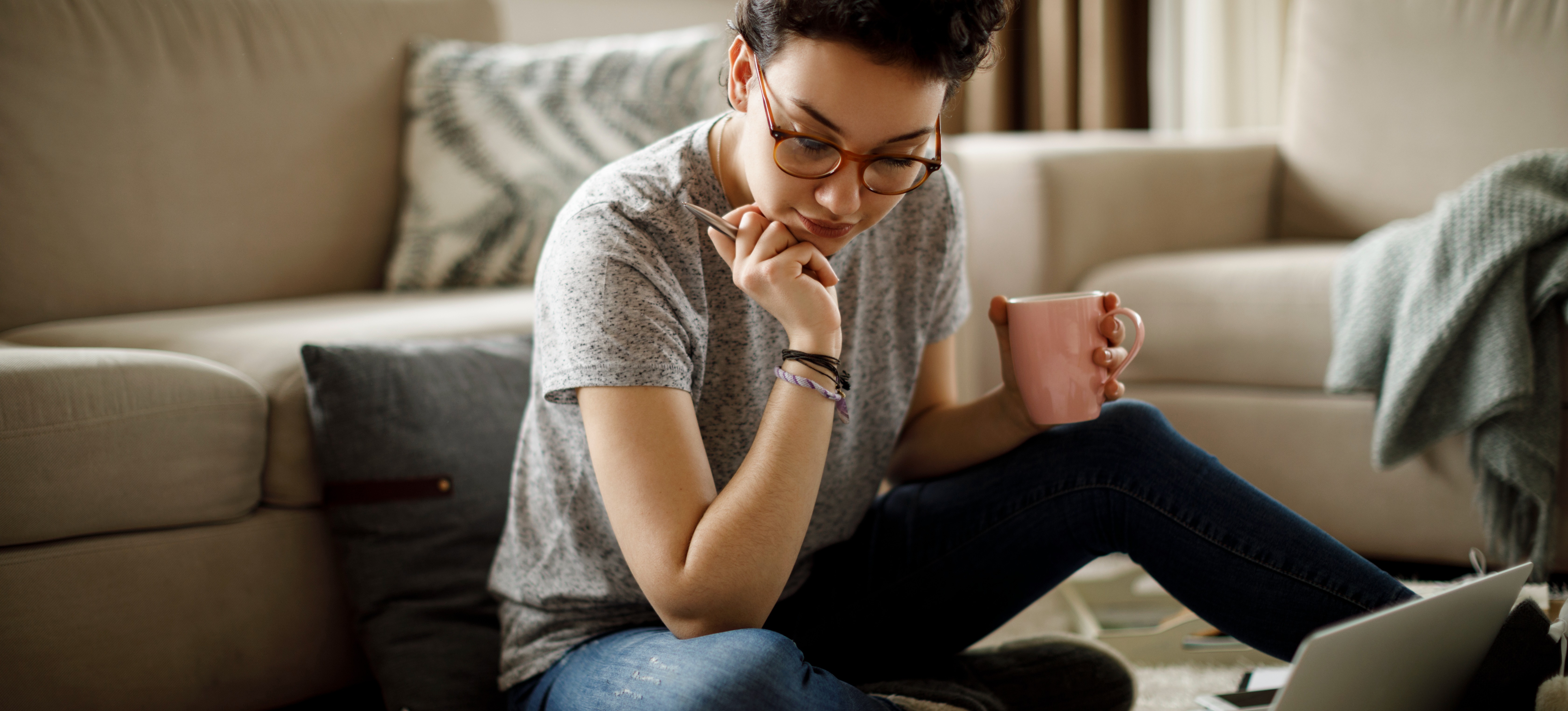 [Featured Image]: A person sitting on a rug looks over their notes as they work on an online interdisciplinary studies degree.
