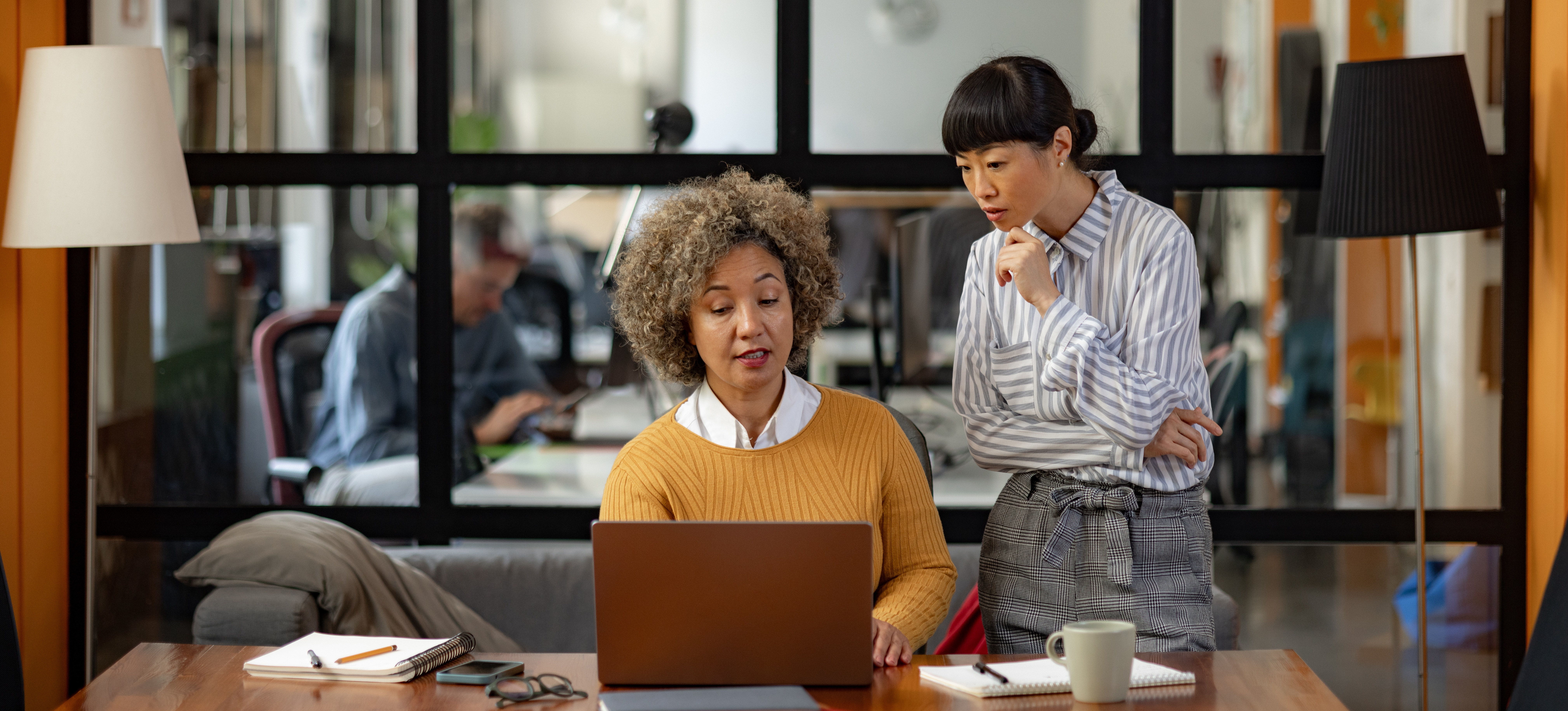 [Featured Image] A marketing automation specialist is having a meeting with a team member about her tasks on a project.