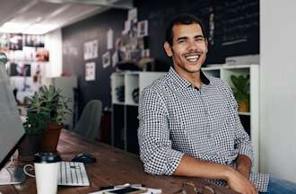 [Featured image] A social media manager sits at a desk with a desktop computer.