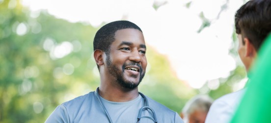 [Feature image] A health educator wearing a blue shirt is talking to members of the community about health wellness issues.