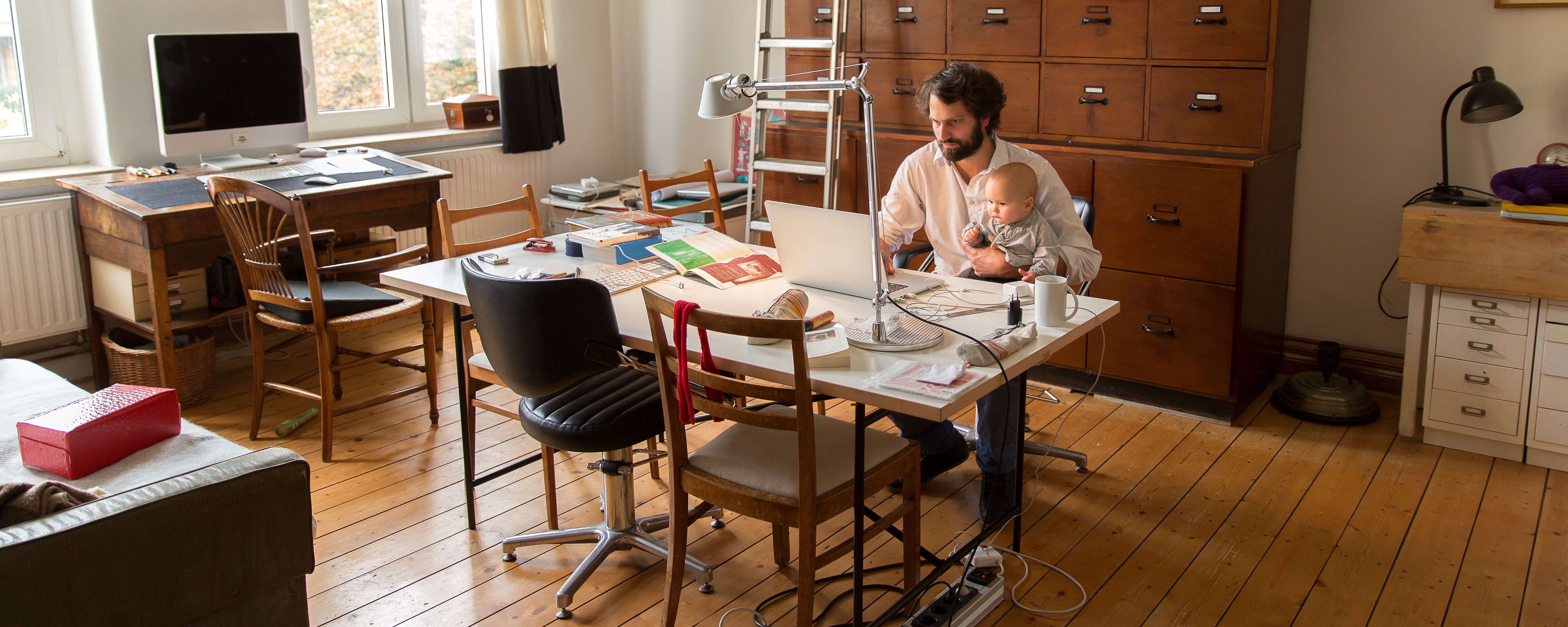 [Featured Image] A stay-at-home parent holding their newborn works for their high-paying entry-level remote job. 