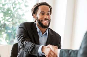 [Featured image] Two men shake hands at a business meeting about b2b marketing.