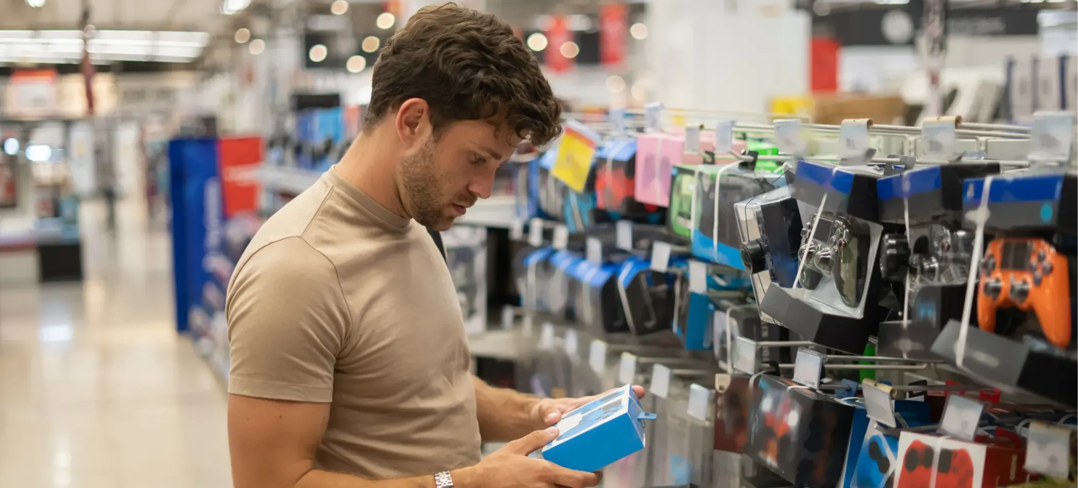 [Featured image] A customer in a large department store browses the selection of game controllers, which are examples of captive product pricing.
