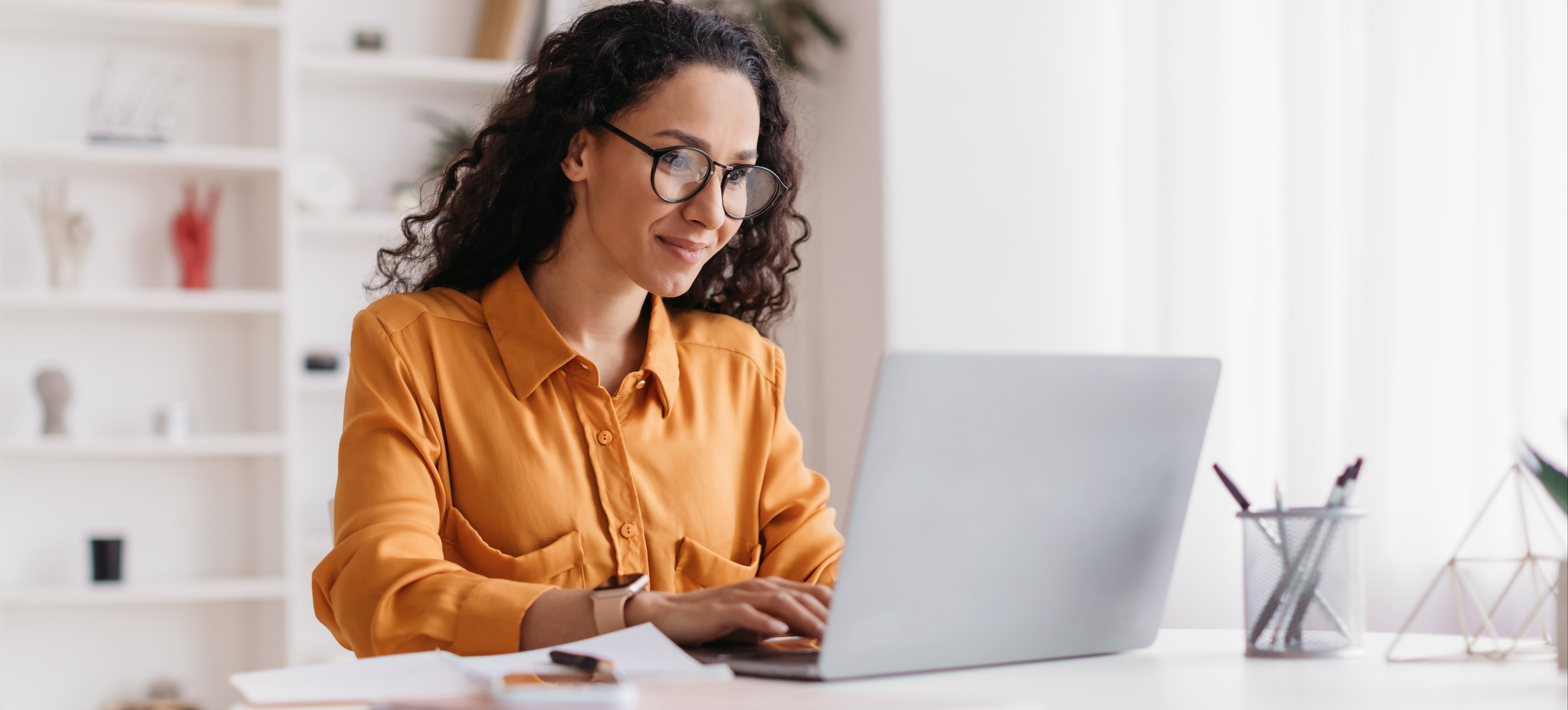 [Featured image] A person in an orange shirt works on a laptop at a white table, researching how long you should stay at a job.