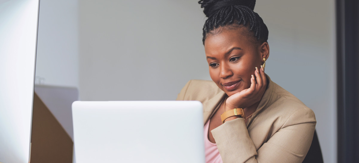 [Featured Image] A technical writer sits at their desk and uses their laptop for work. 
