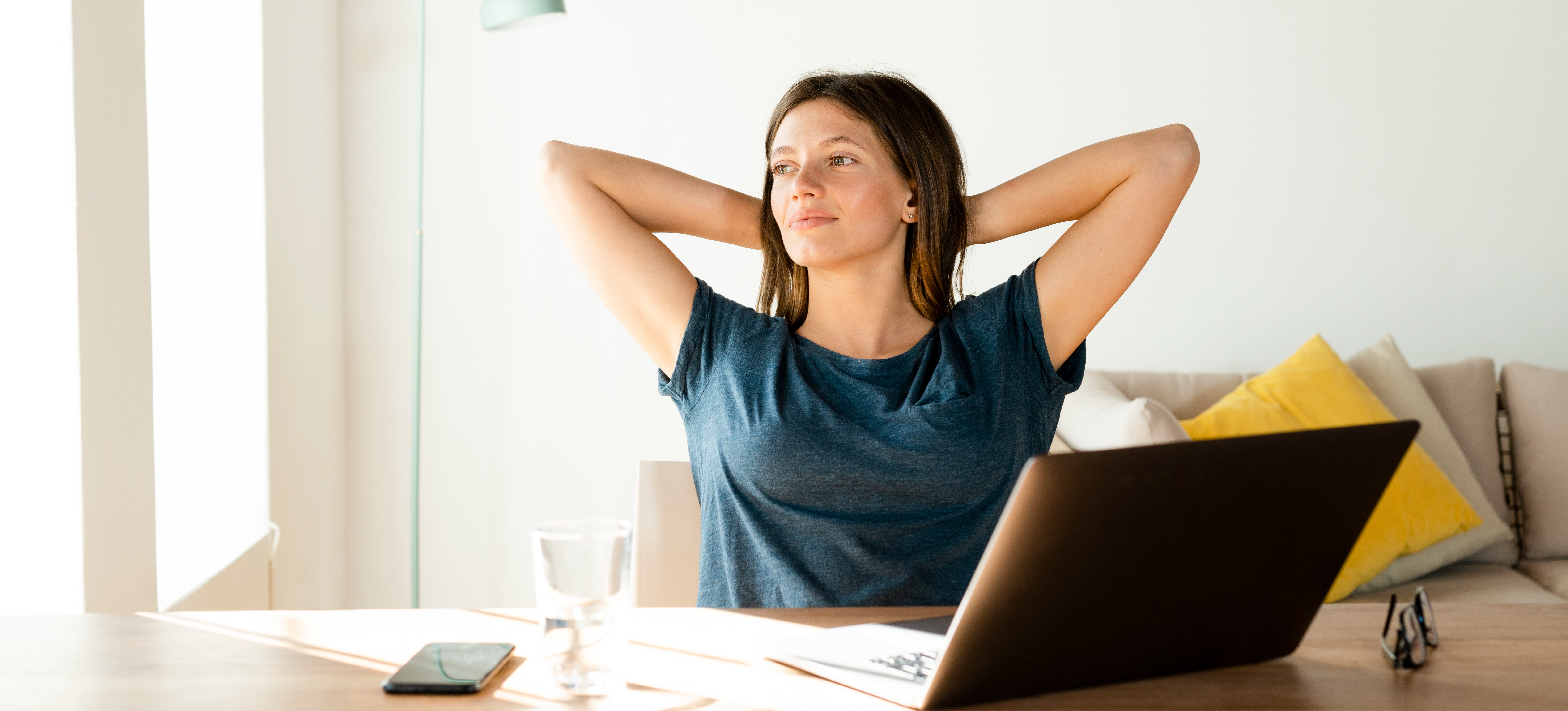 [Featured image] A person relaxes at a desk behind their laptop and thinks about making a career change to cybersecurity.  
