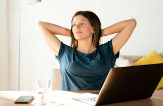 [Featured image] A woman relaxes at a desk behind her laptop and thinks about making a career change to cybersecurity.  
