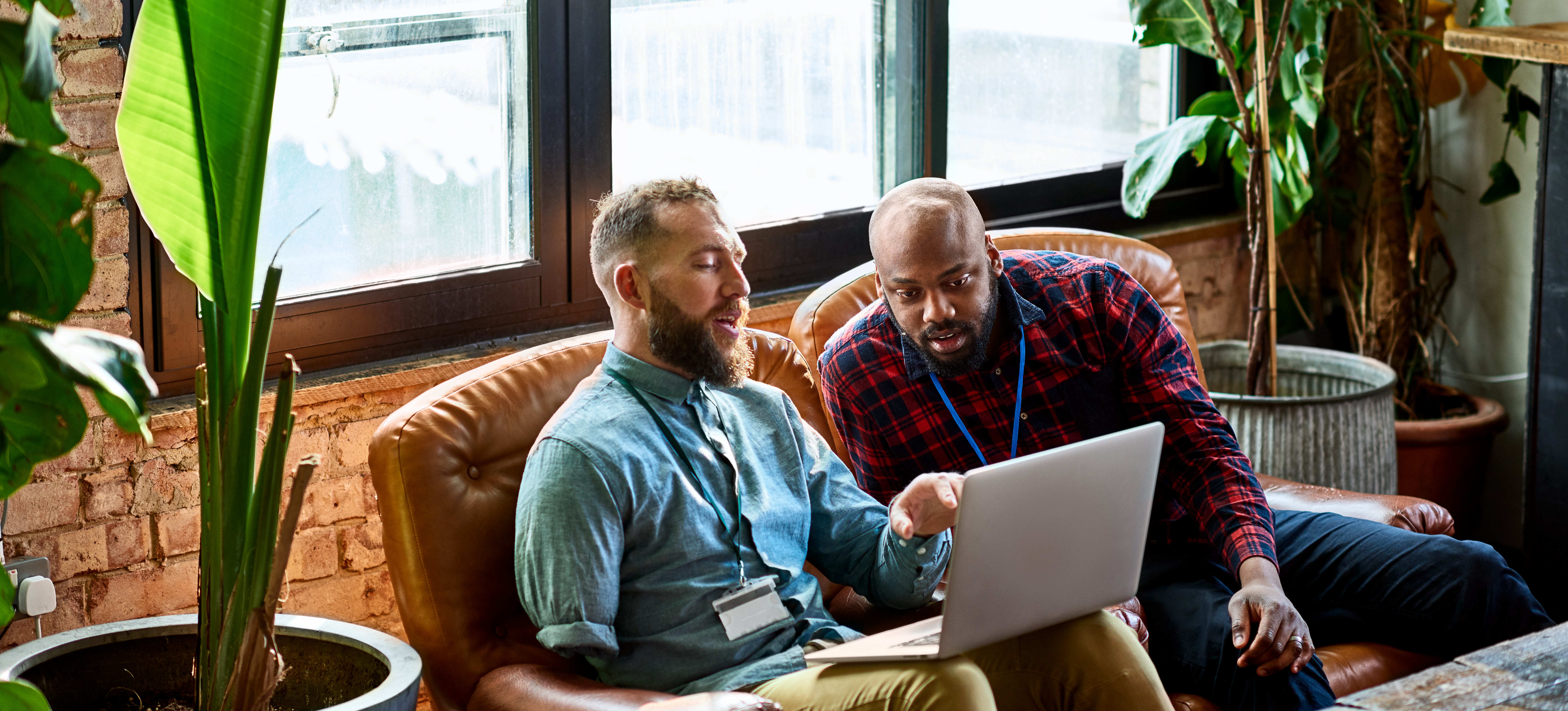 [Featured Image] Two work colleagues use a laptop to analyze work related bayesian statistics