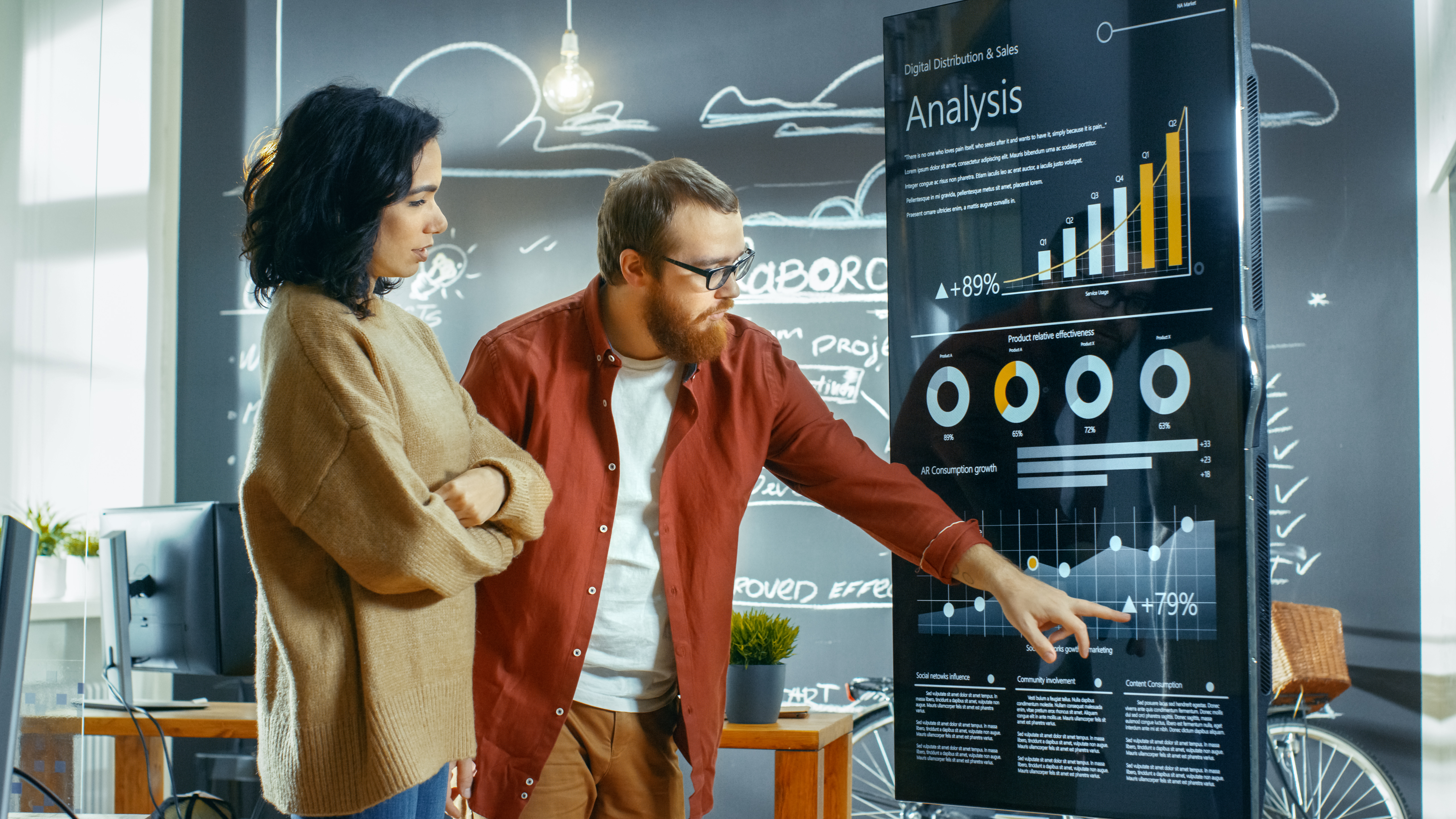 [Feature Image] Statisticians study charts in front of a blackboard.