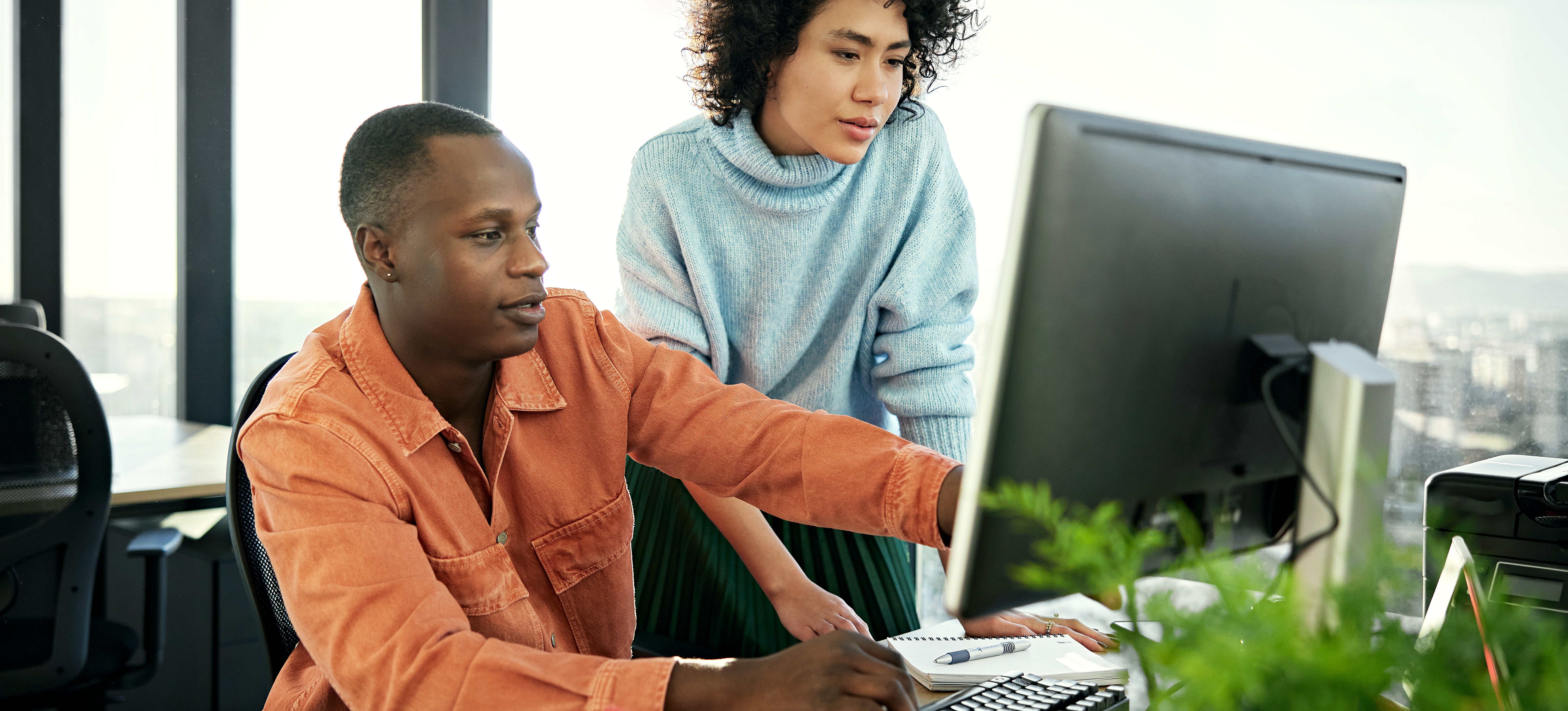 [Featured Image] A computer scientist collaborates with a colleague in an office setting.
