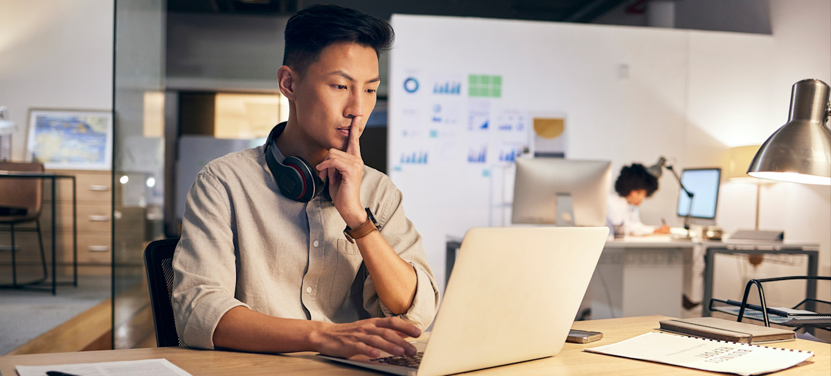 [Featured Image] A programmer sits at their desk and helps their company integrate AI.  