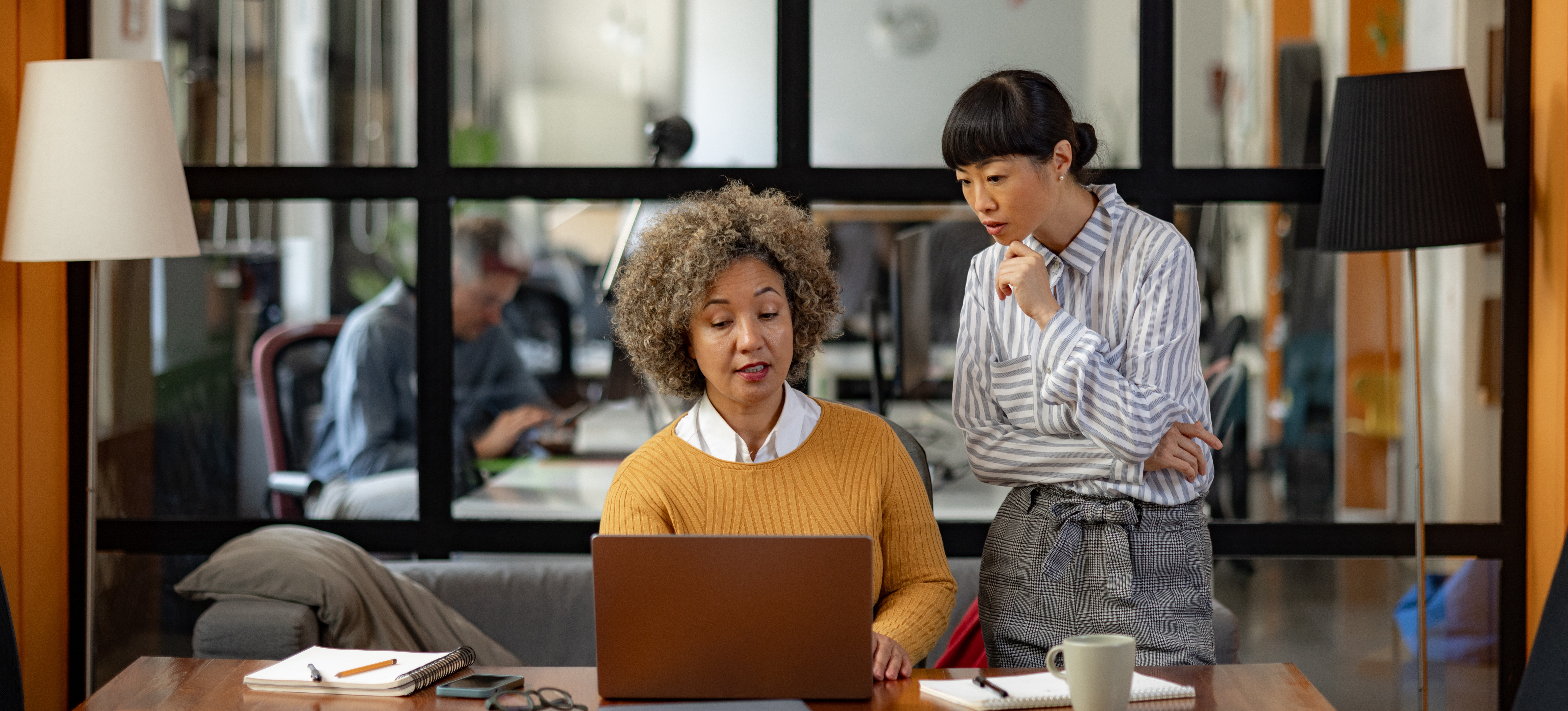 [Featured Image] A business professional is at a laptop teaching the role of email marketing to a new hire.
