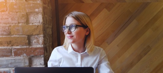 [Featured image] A woman working on her business administration degree is sitting in front of her desktop working on an assignment.