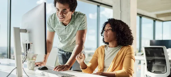 [Featured Image] Two programmers prepare for a pair programming project as part of their software development work.
