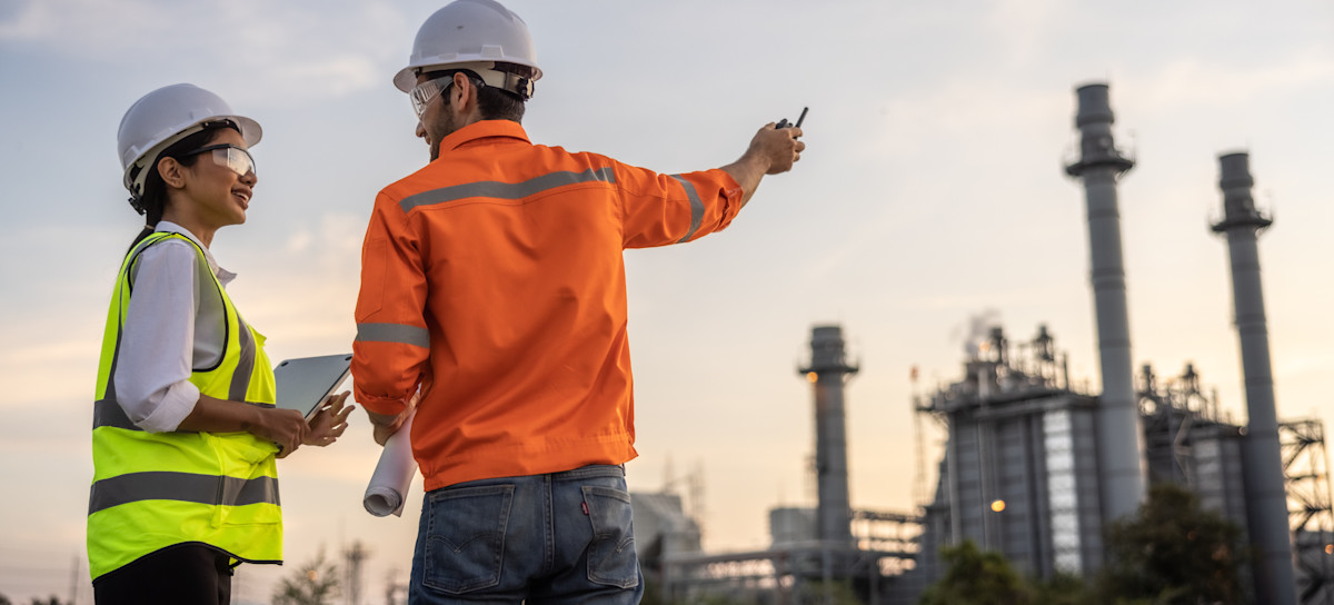 [Featured Image]: A compliance analyst and member of the leadership team stand outside and discuss findings.
