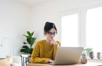 [Featured image] A woman is at home using her laptop to search for entry-level marketing jobs.
