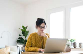 [Featured image] A woman is at home using her laptop to search for entry-level marketing jobs.
