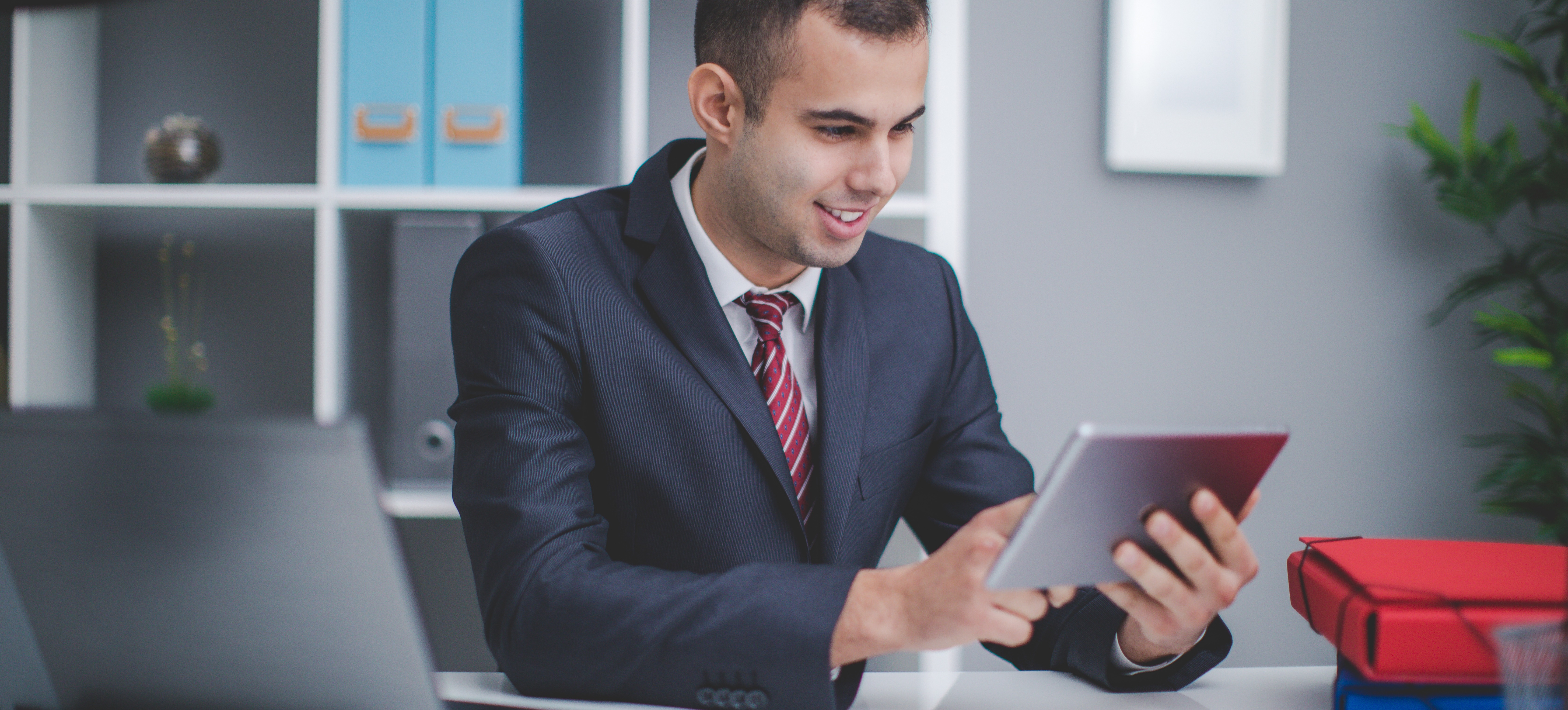 [Featured Image] A credit analyst works on a tablet in their office.  